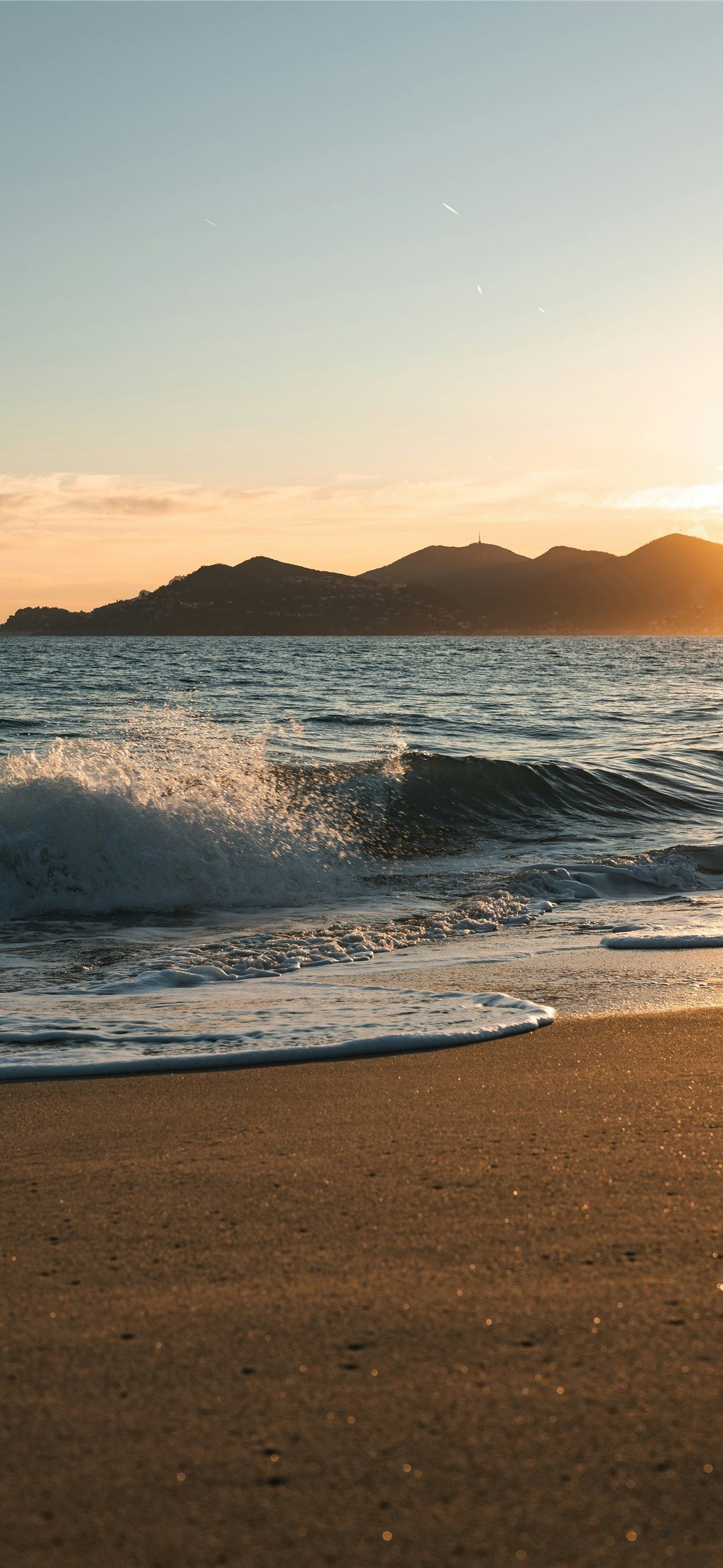 1290x2796 Gentle waves wash onto a sandy beach at sunset iPhone Wallpaper Free Download