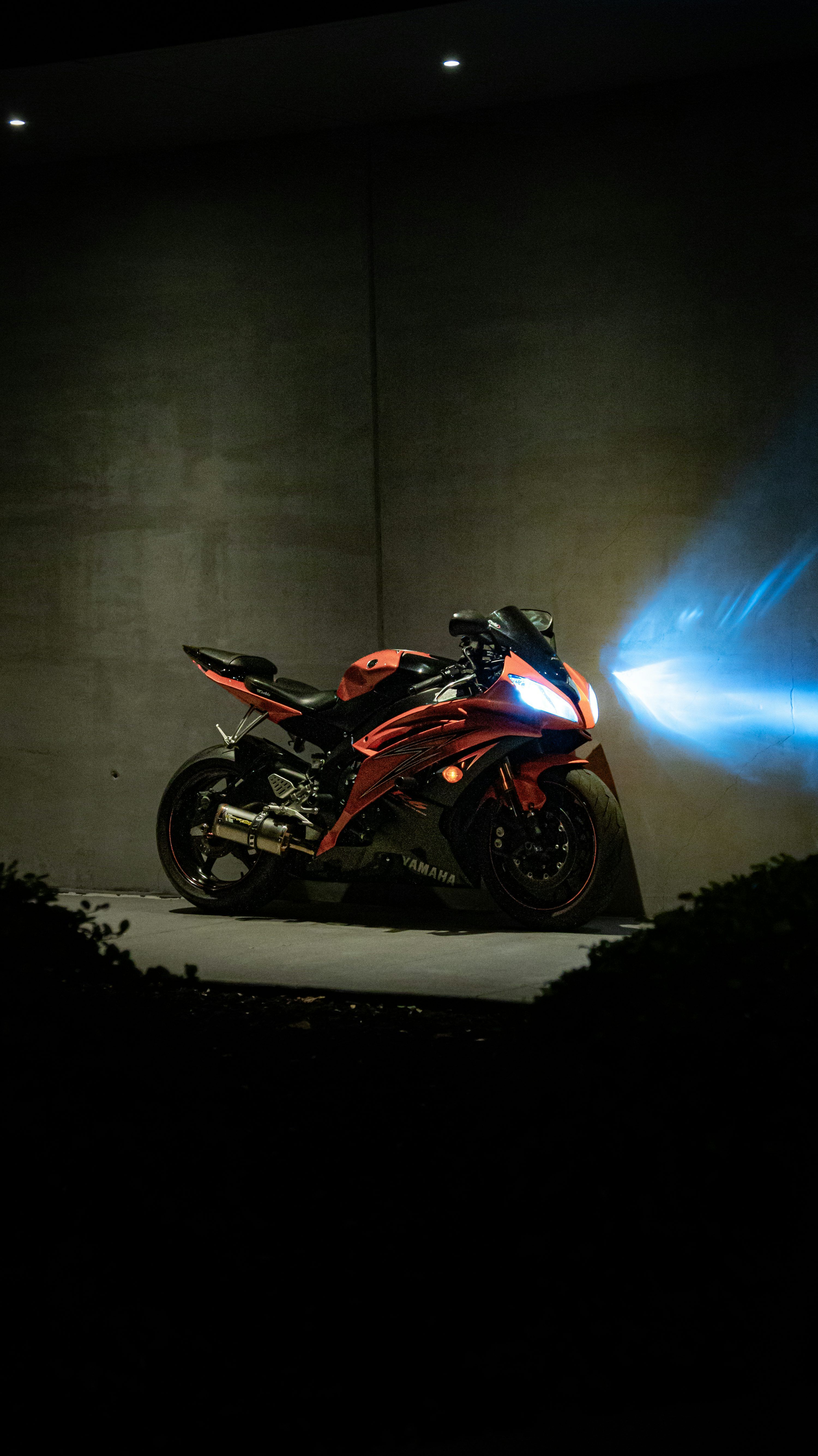 3000x5338 A red motorcycle with bright blue headlight beam. photo