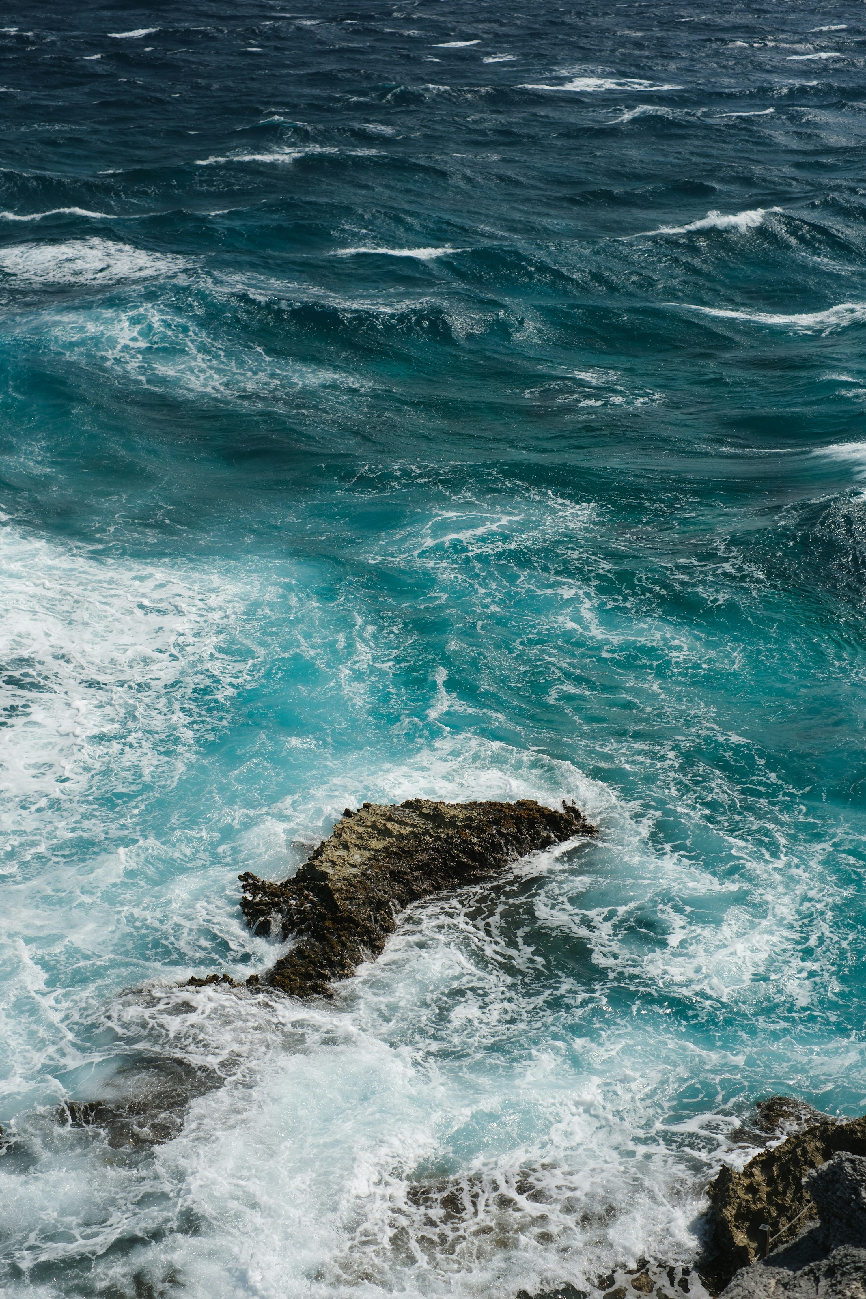 3000x4500 Rough turquoise waves crash against a rocky shore