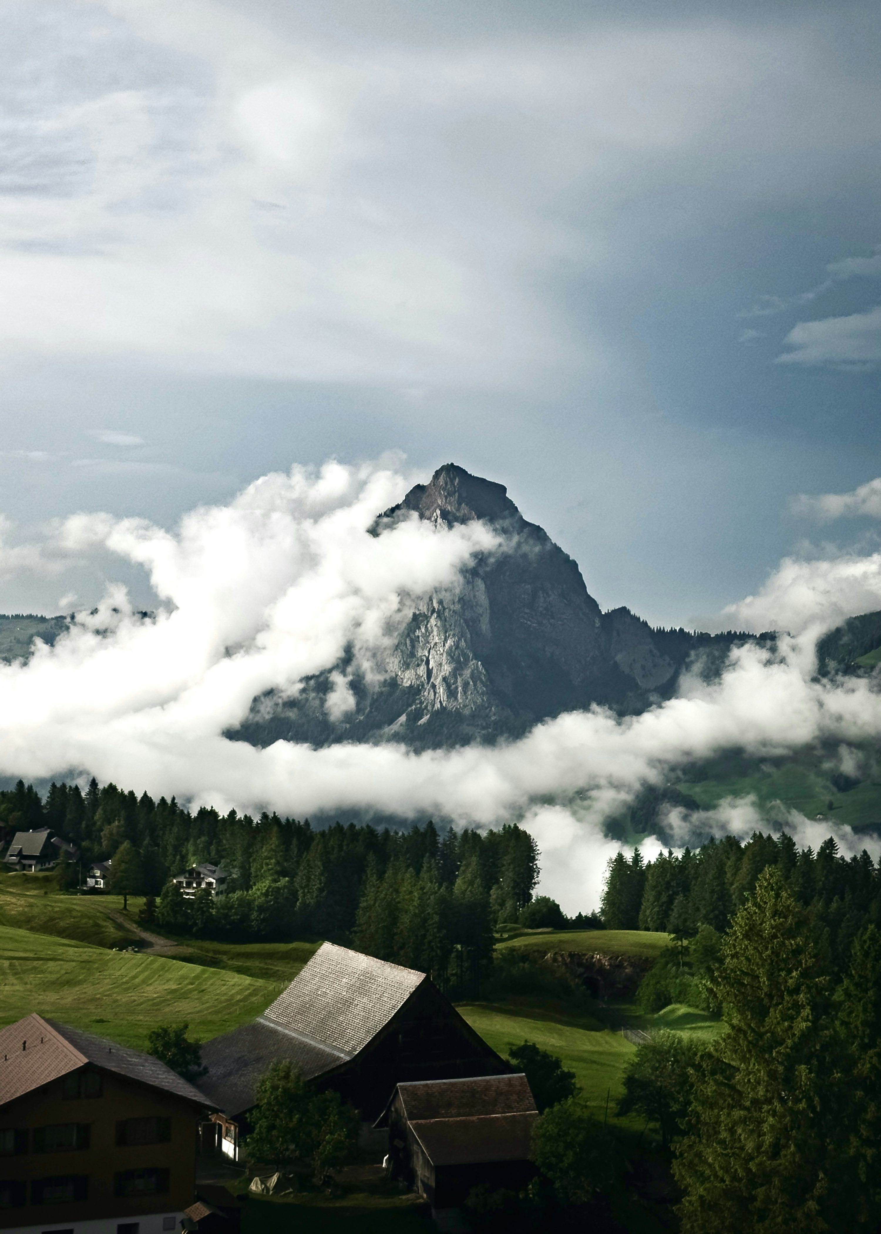 3000x4200 Mountain peak emerges from clouds above green hills