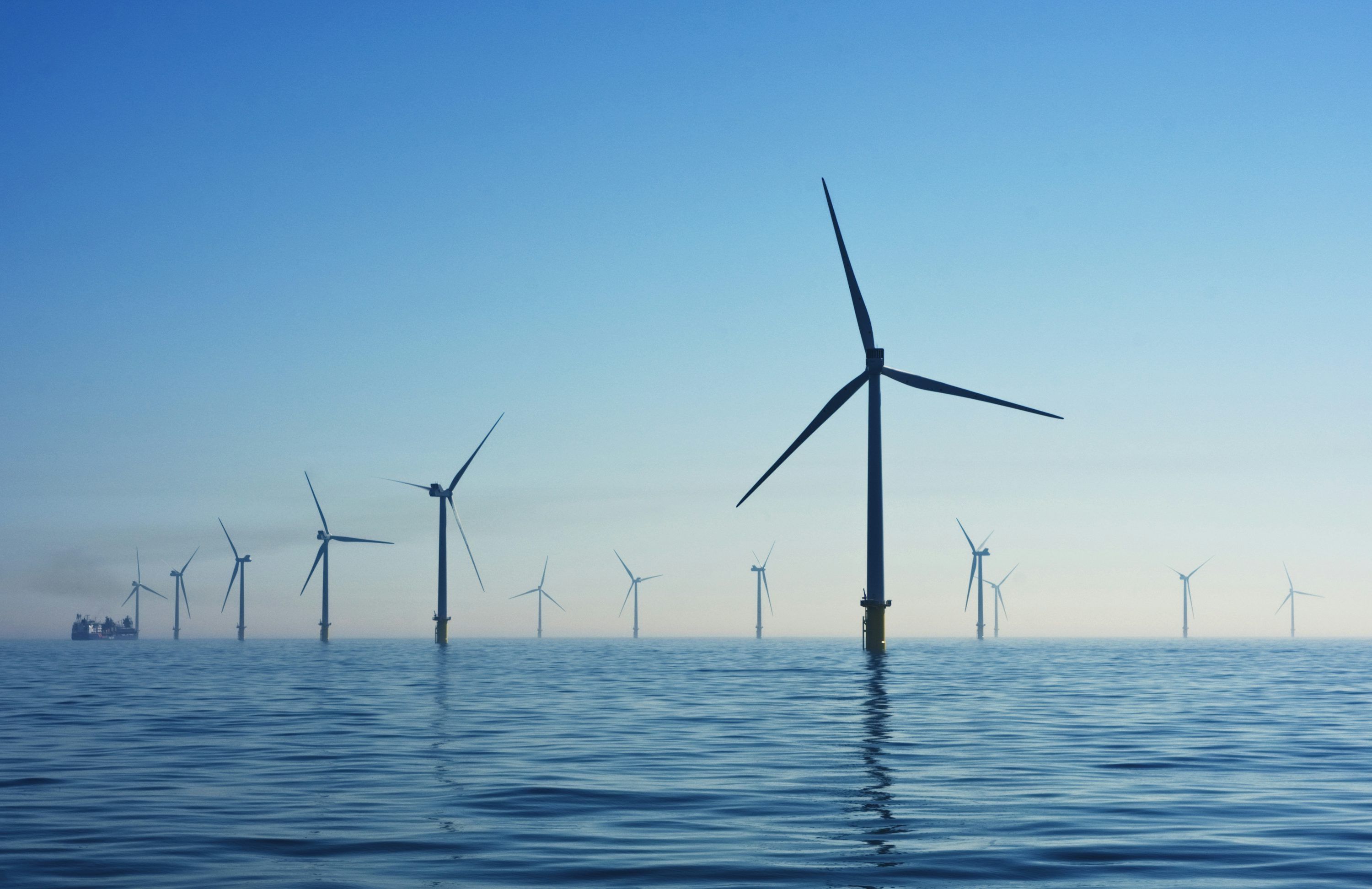 3000x1944 Silhouetted cranes and wind turbines against cloudy sky