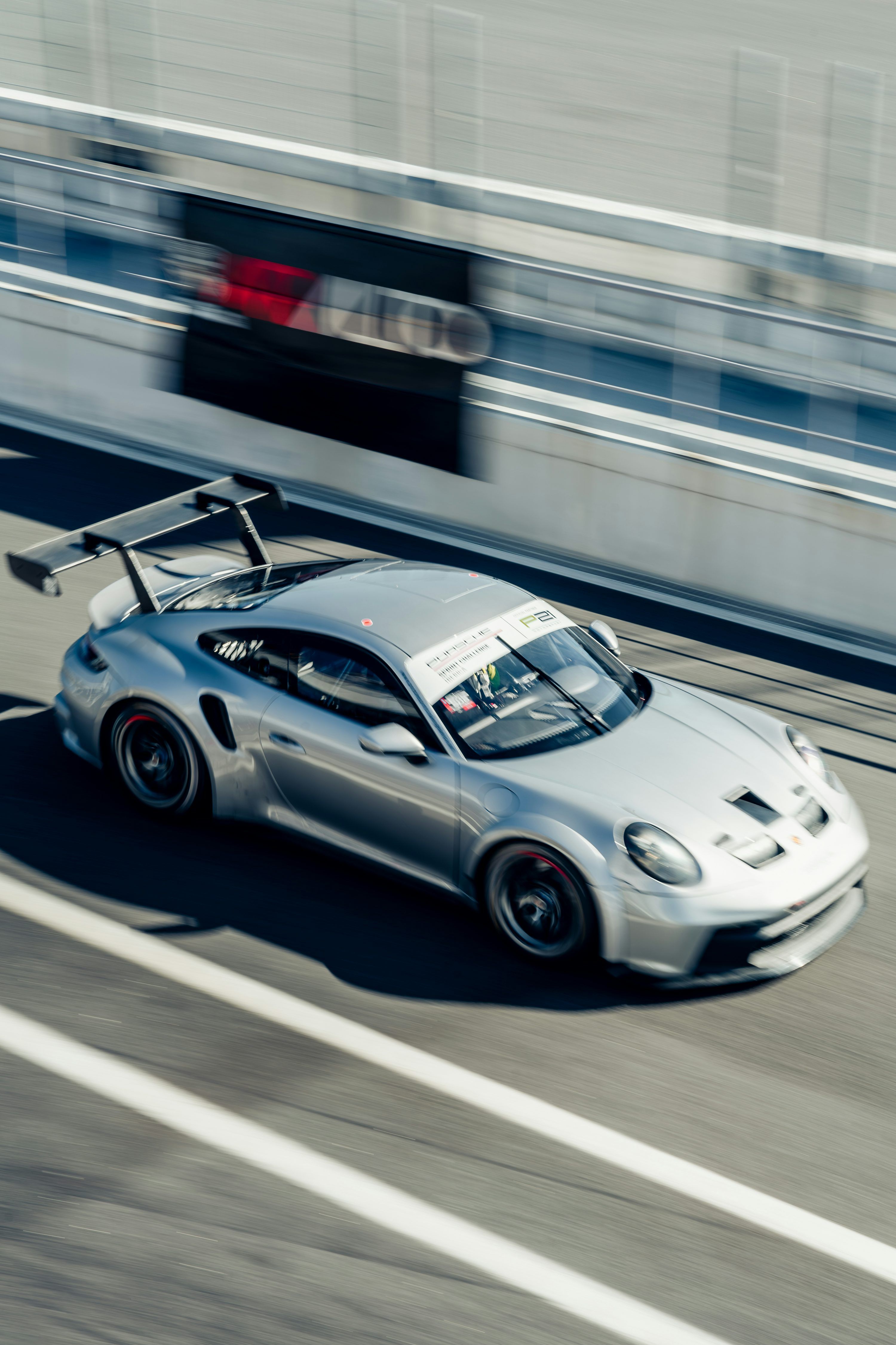 3000x4500 A silver porsche races on a racetrack