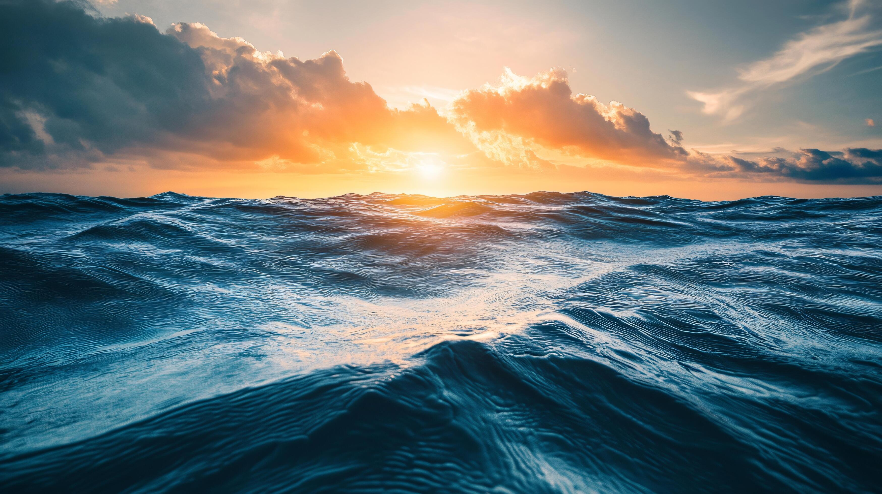 3497x1960 The ocean is calm and the sun is setting, creating a beautiful and serene atmosphere. The water is a deep blue color, and the sky is filled with clouds, adding to the