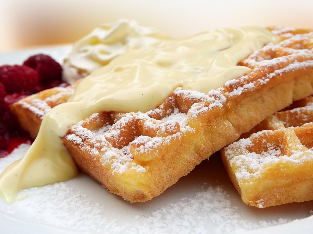 1024x768 A plate of waffles with cream and raspberries. Waffles