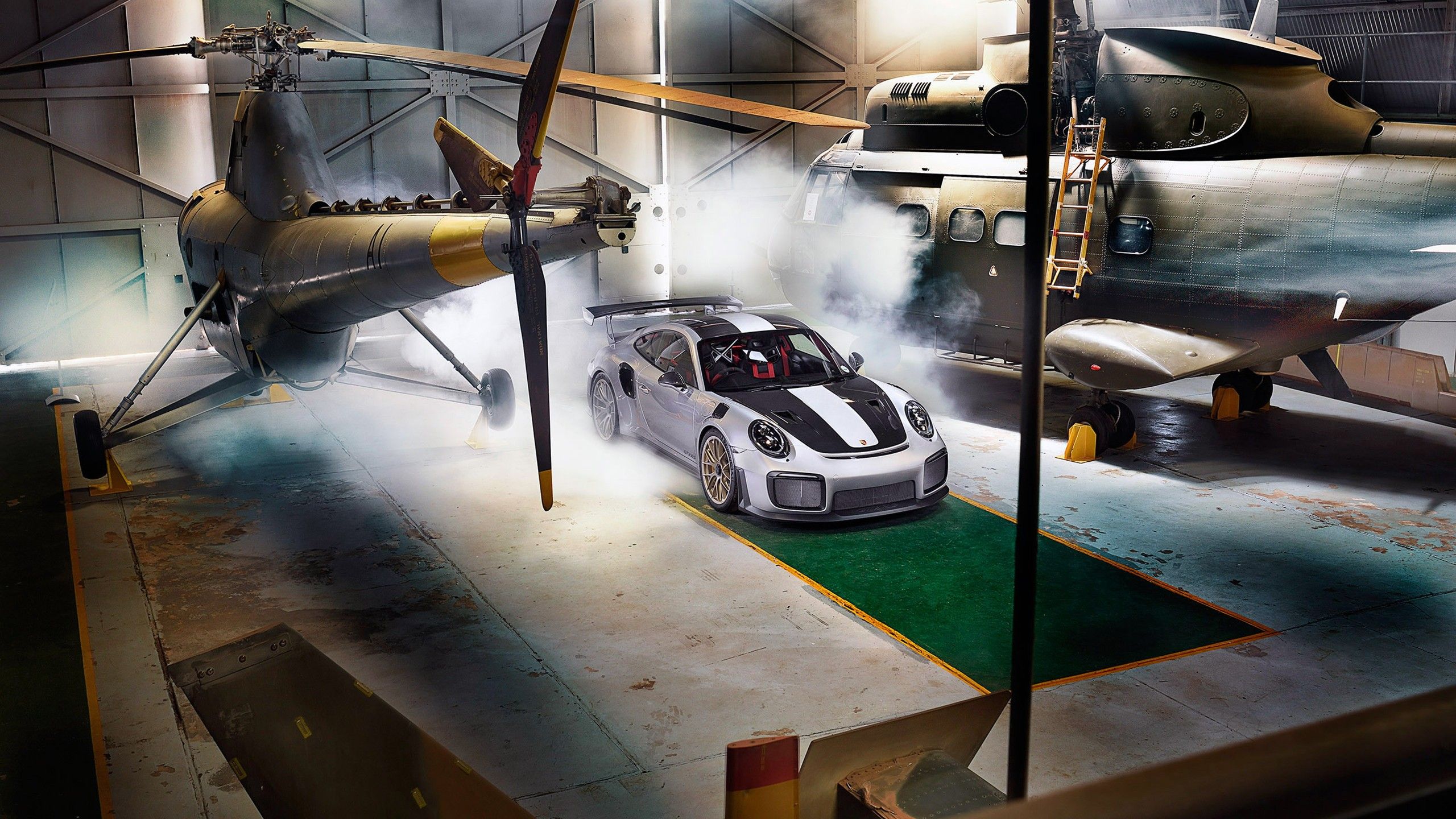 2560x1440 Porsche 911 GT2 RS in a hangar with helicopters Desktop wallpaper 1920x1080