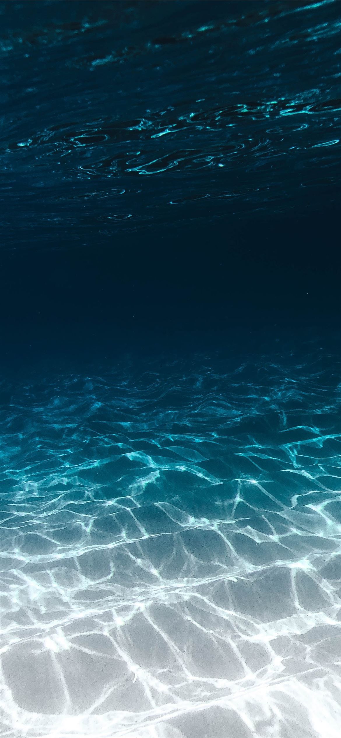 1170x2532 grey sand under blue clear water iPhone 12 Wallpaper Free Download