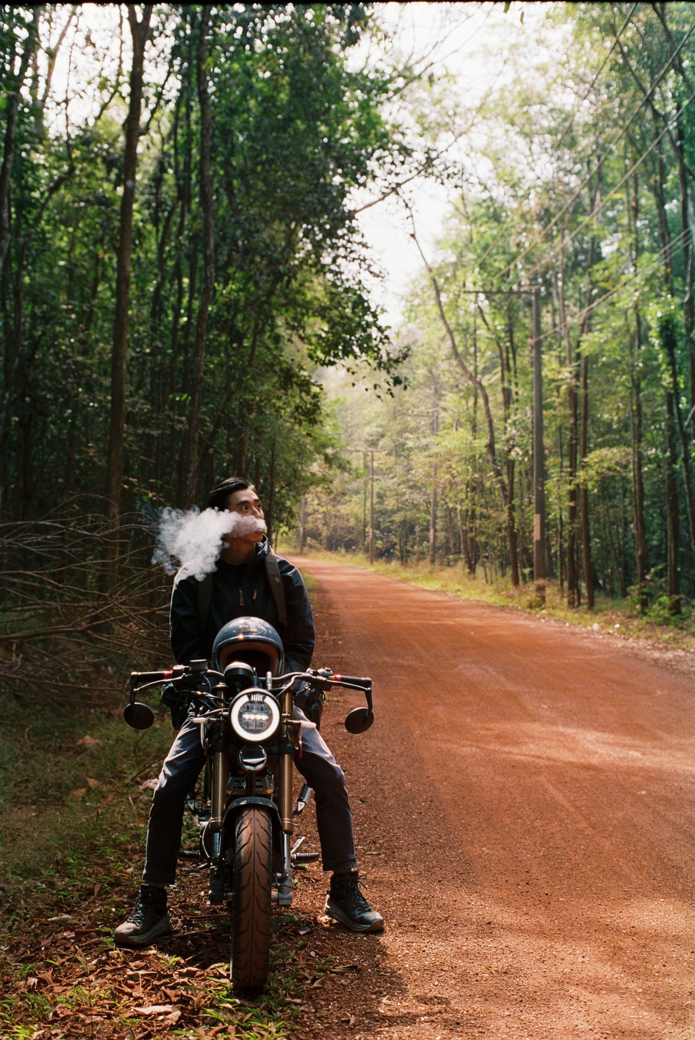 2431x3639 Smoking Biker Sits in Motorcycle on Side of Rural Road · Free
