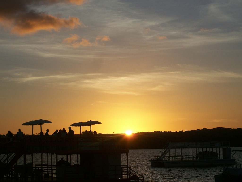 1024x768 A group of people sitting on top of a boat at sunset