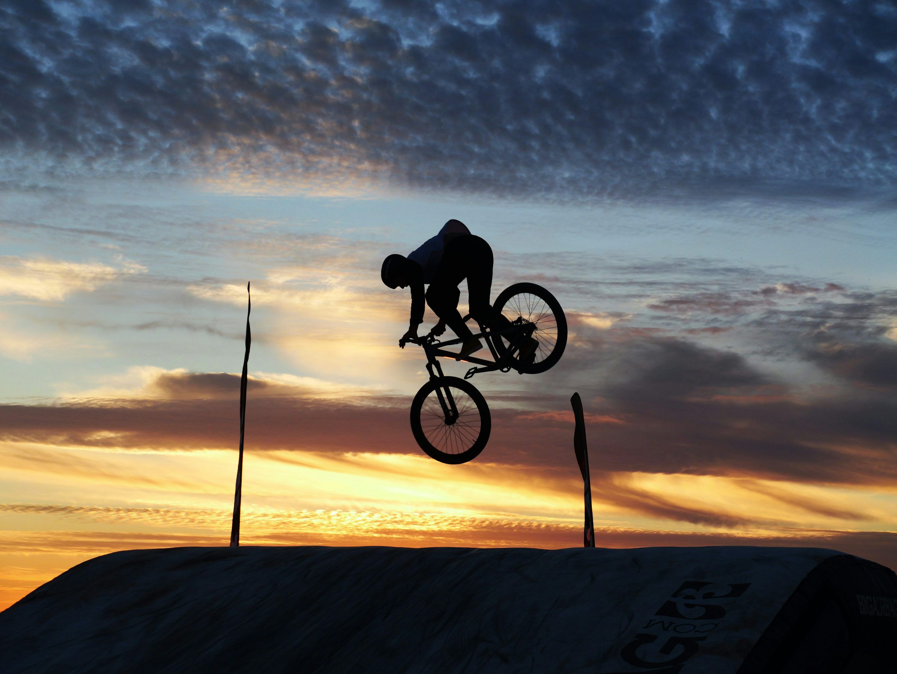 3000x2253 Cyclist performing a jump against a colorful sunset sky