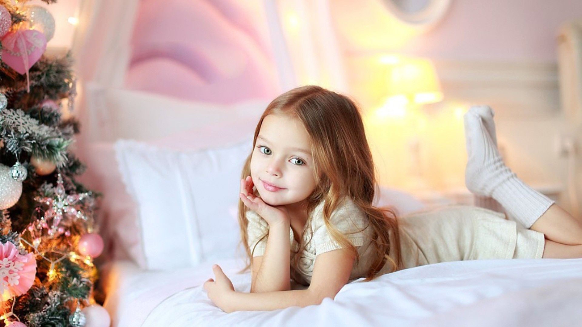1920x1080 Beautiful Cute Little Girl Is Lying Down On White Bed Wearing White Dress And Socks In Colorful Lights Background HD Cute Wallpaper