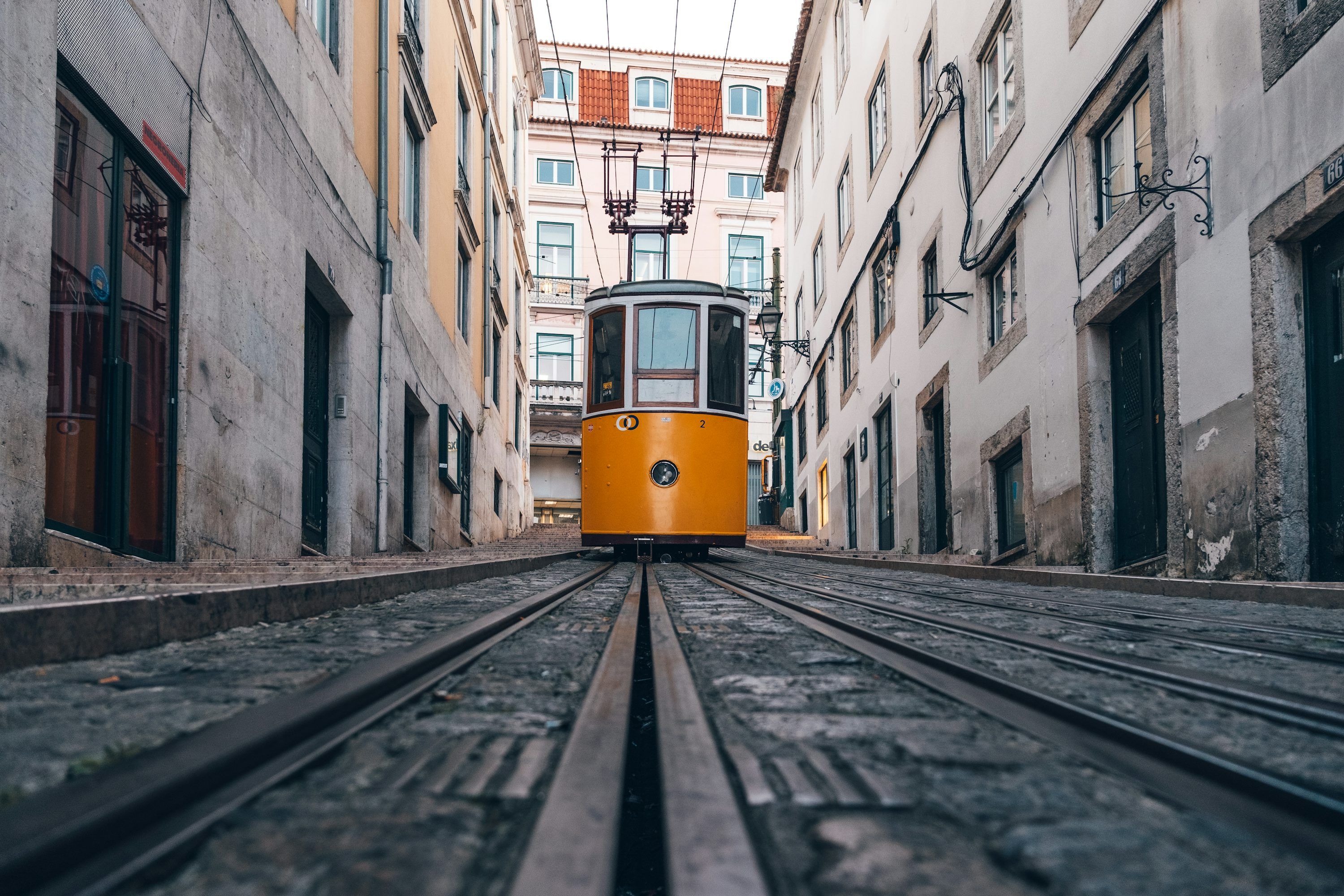 3000x2000 A yellow tram on tracks in a narrow city street