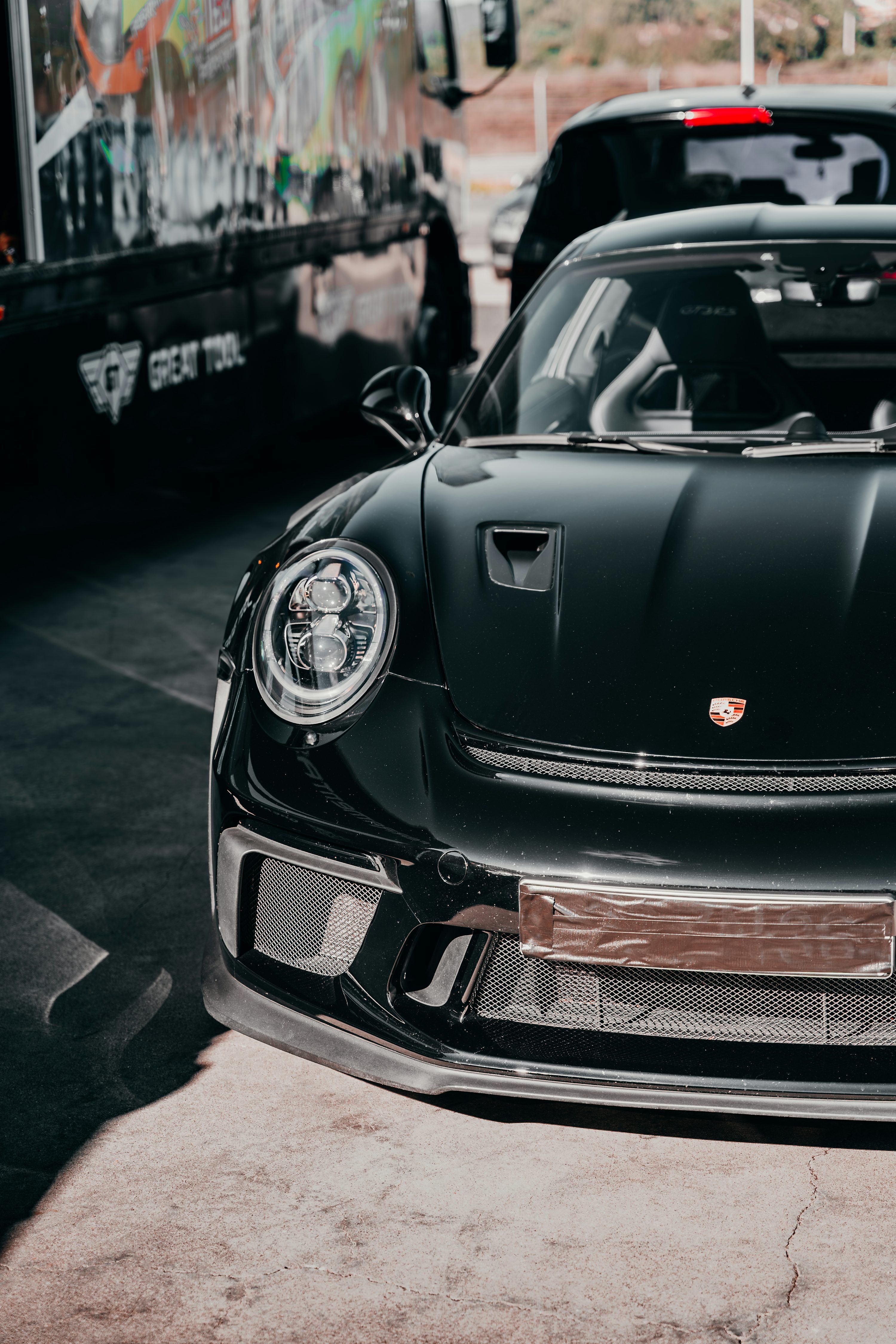 3000x4500 A sleek black porsche shines in the sunlight