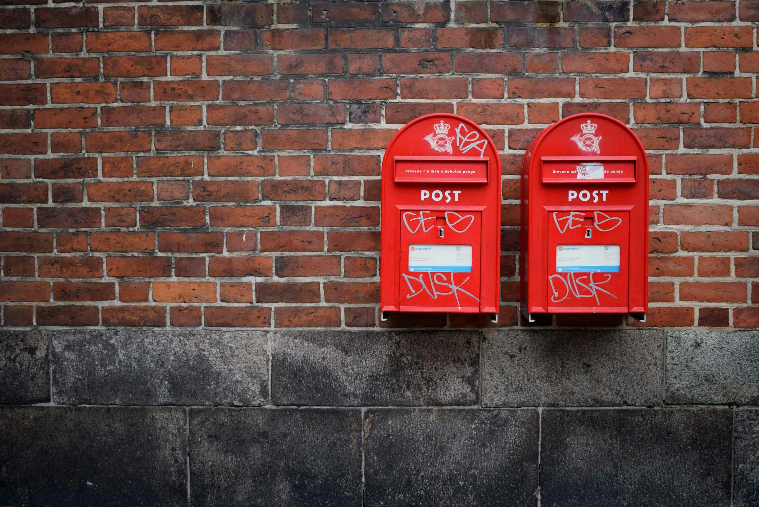 3000x2006 Photo of two red post boxes mounted in brown concrete wall