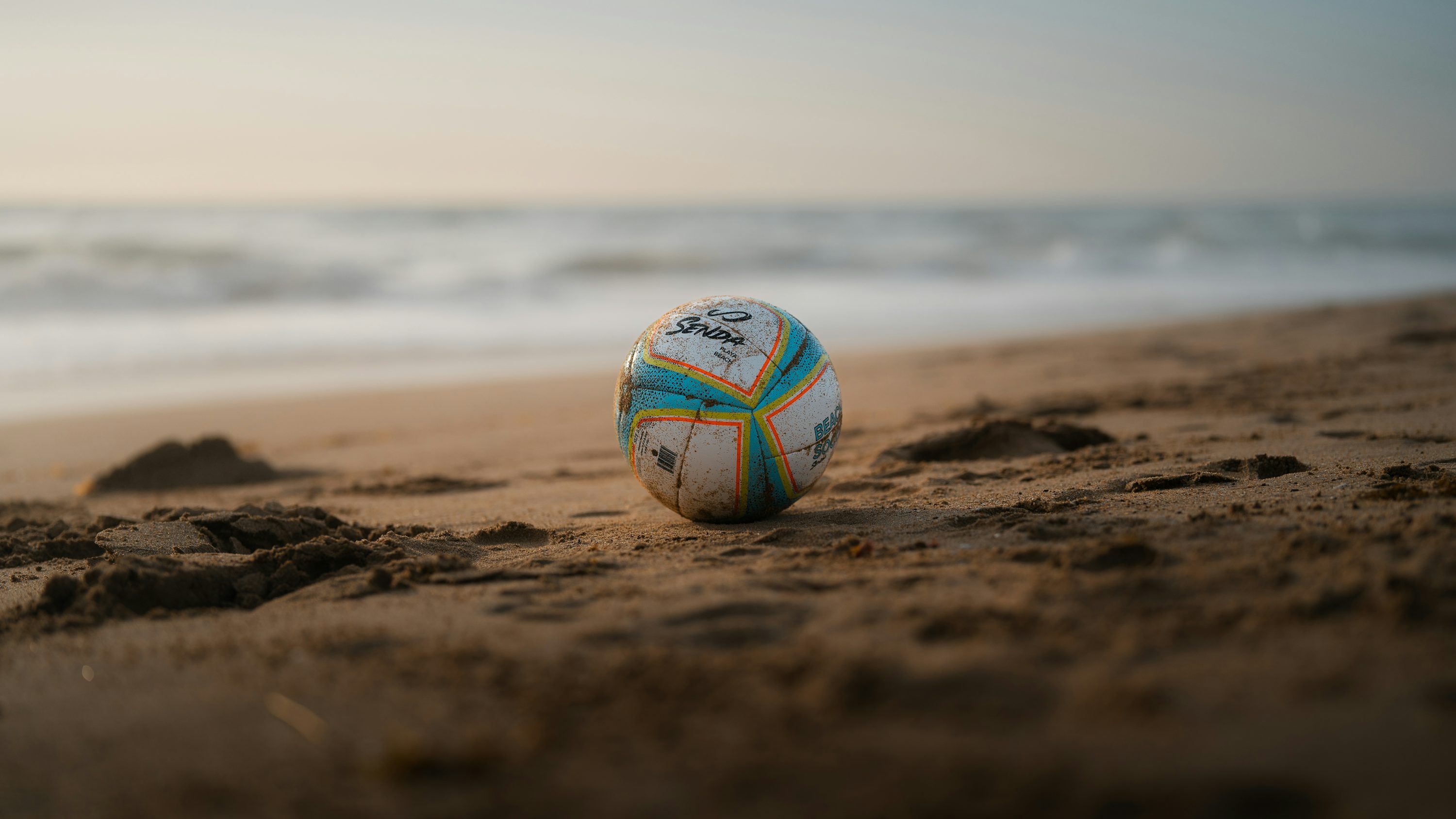 3000x1688 A soccer ball rests on the sandy beach
