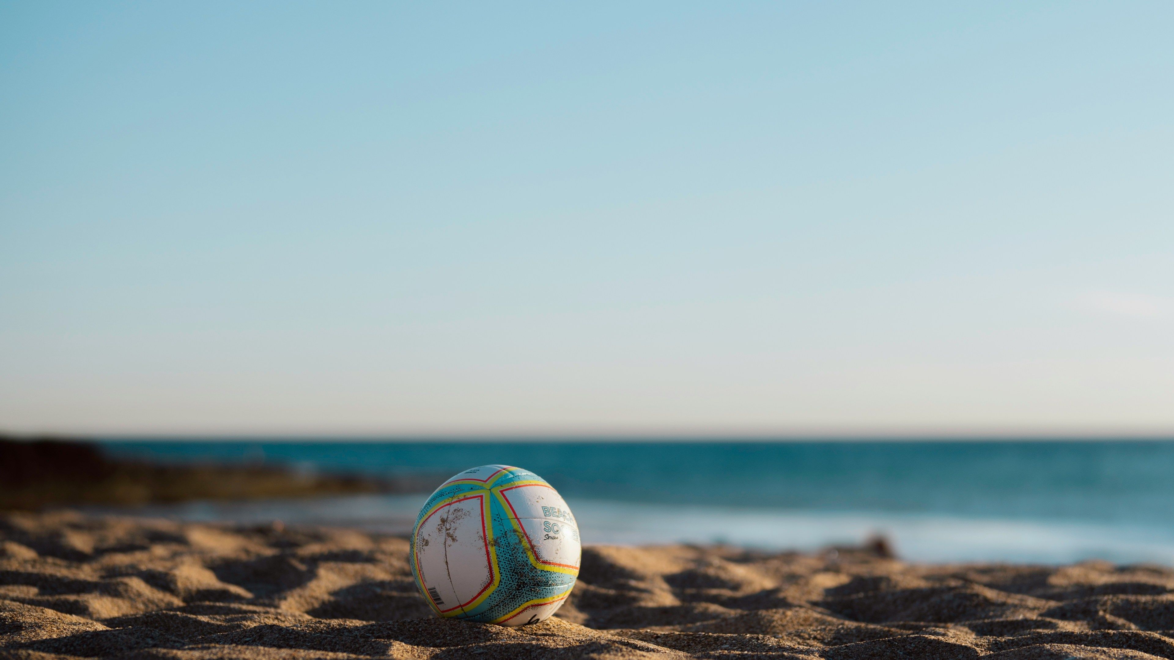3840x2160 A soccer ball rests on the sandy beach