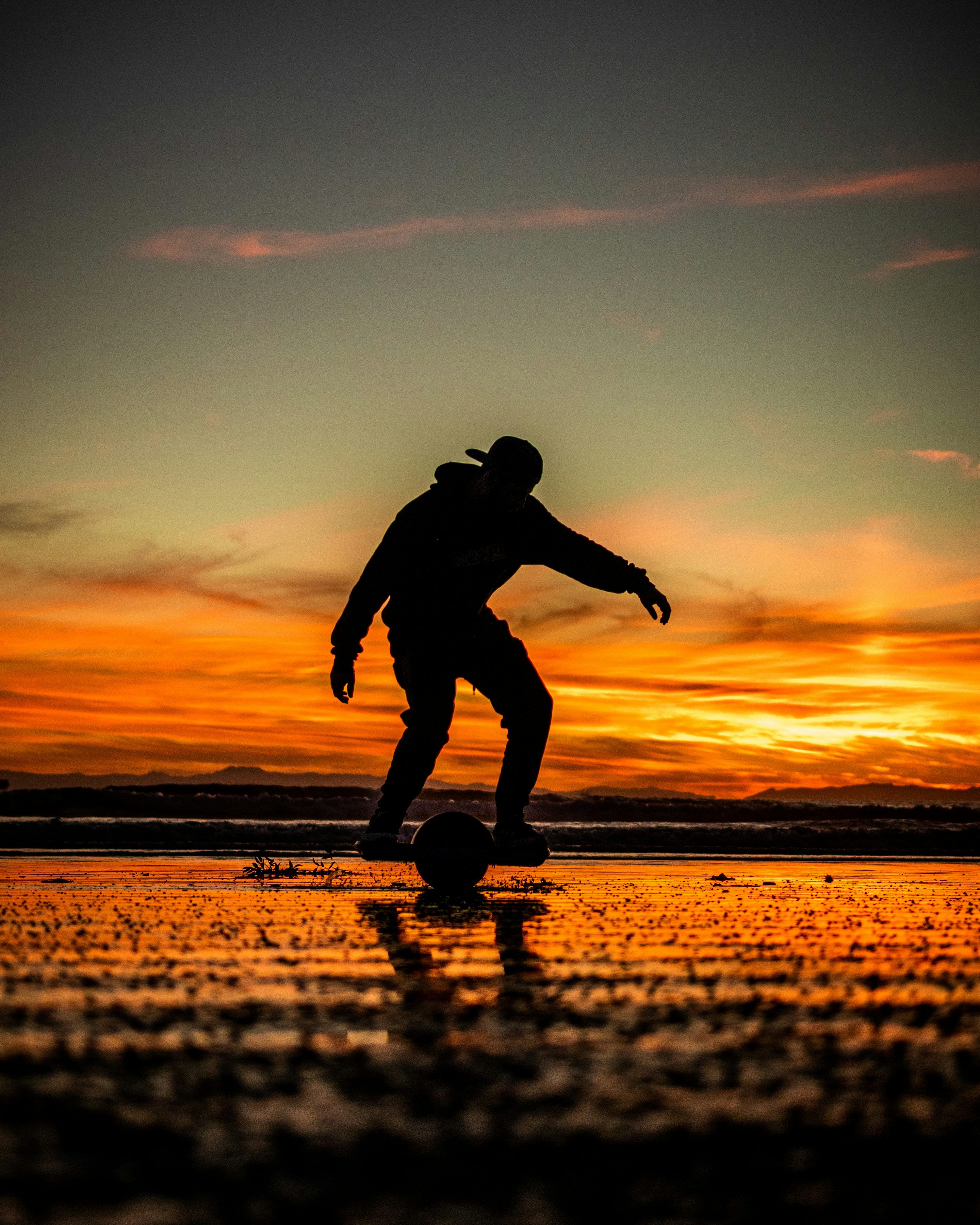 3000x3750 A man riding a skateboard on top of a wet beach
