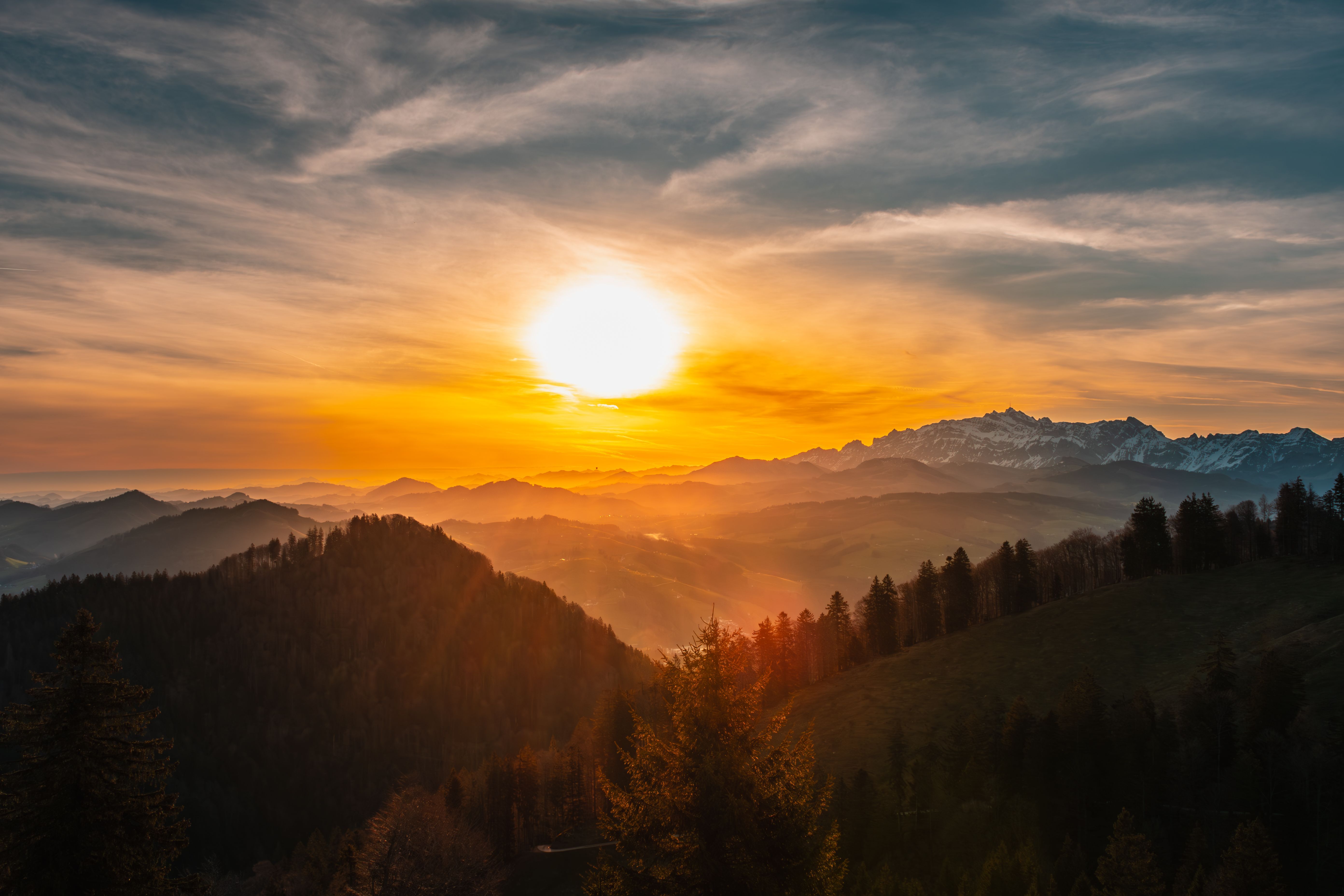 5568x3712 The sun sets over a mountain range with trees and mountains · Free
