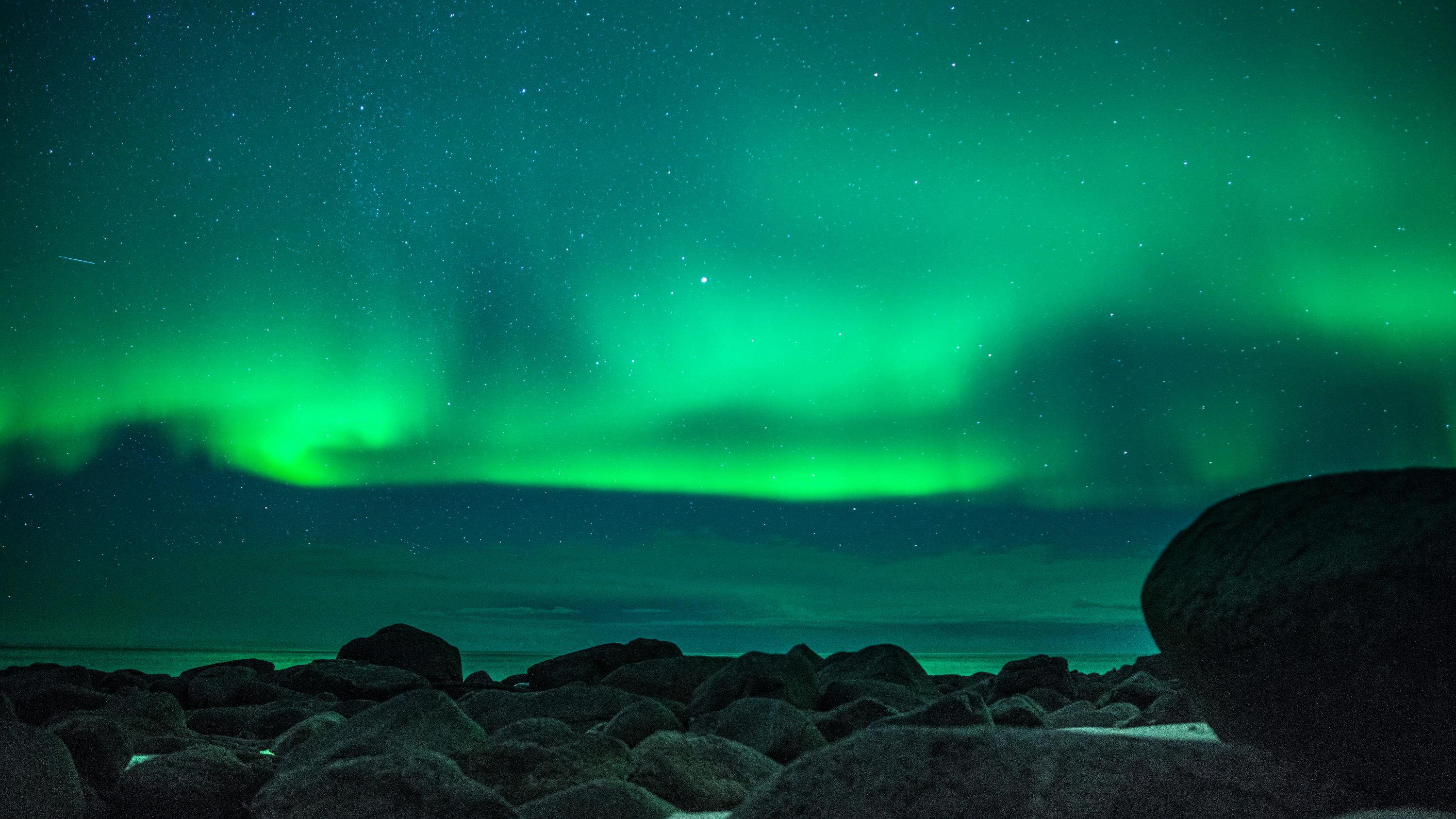 3000x1687 Black rocks near body of water under green sky