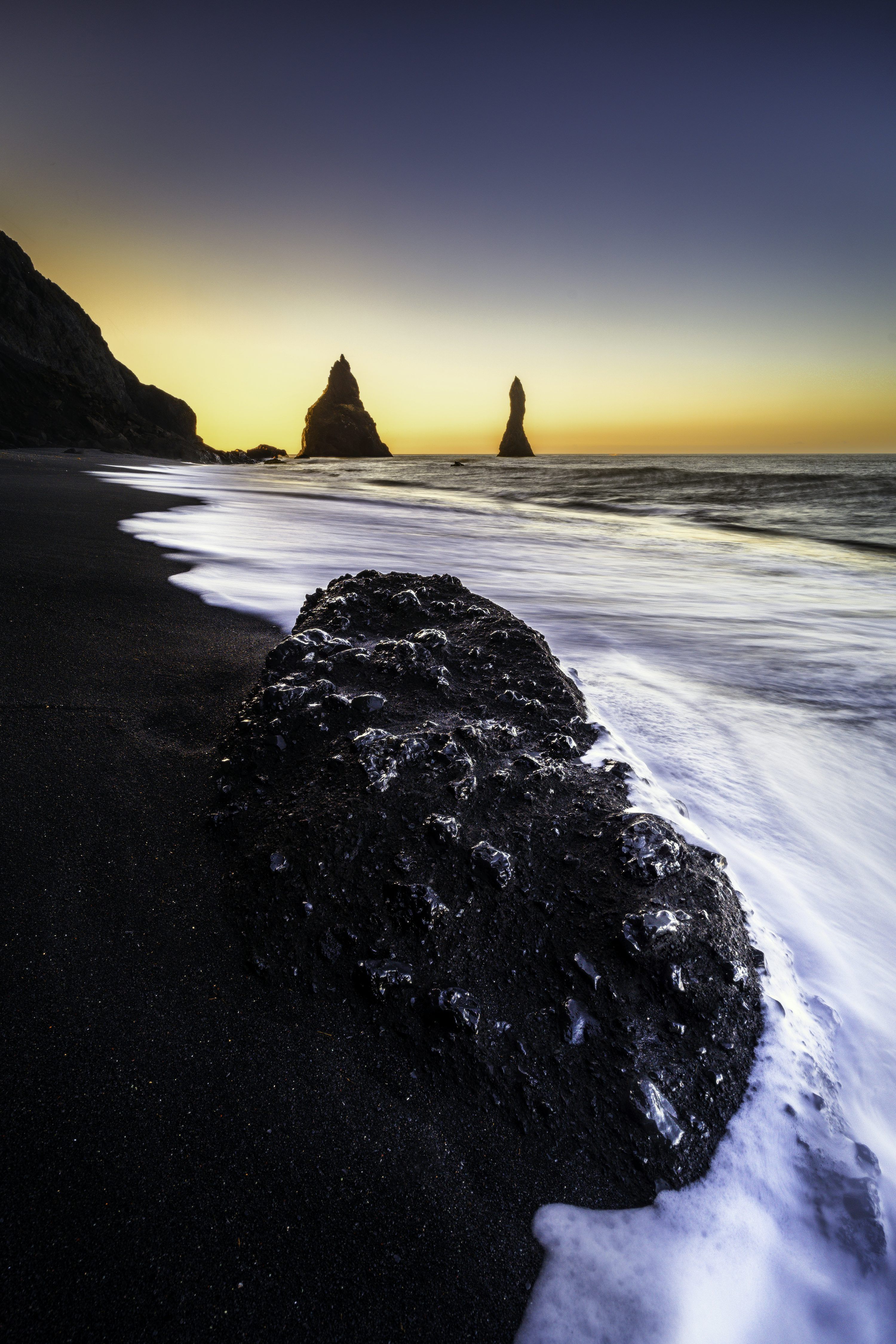3000x4500 A black sand beach with a rock formation in the foreground