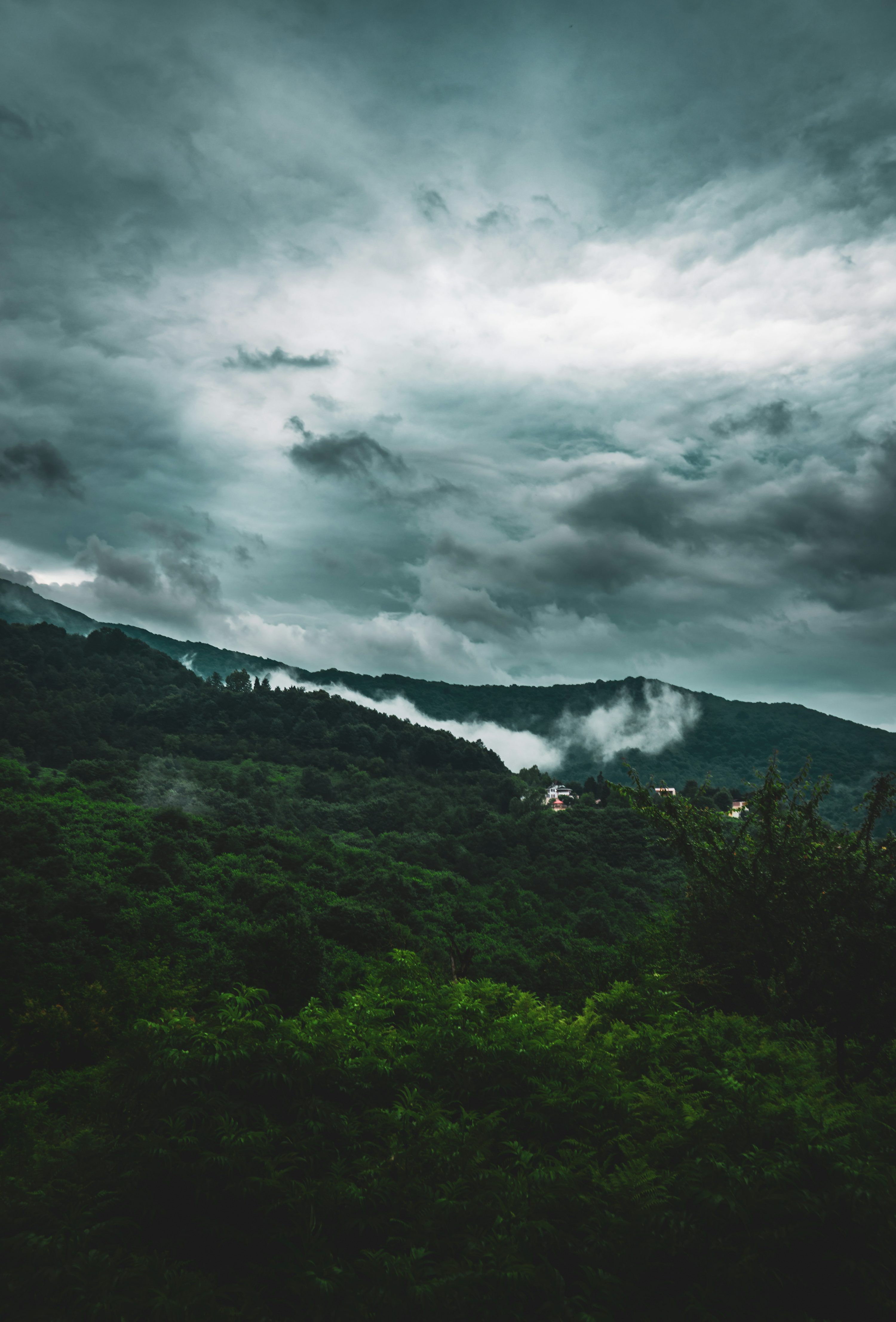 3000x4424 Dark, stormy clouds over lush green mountains
