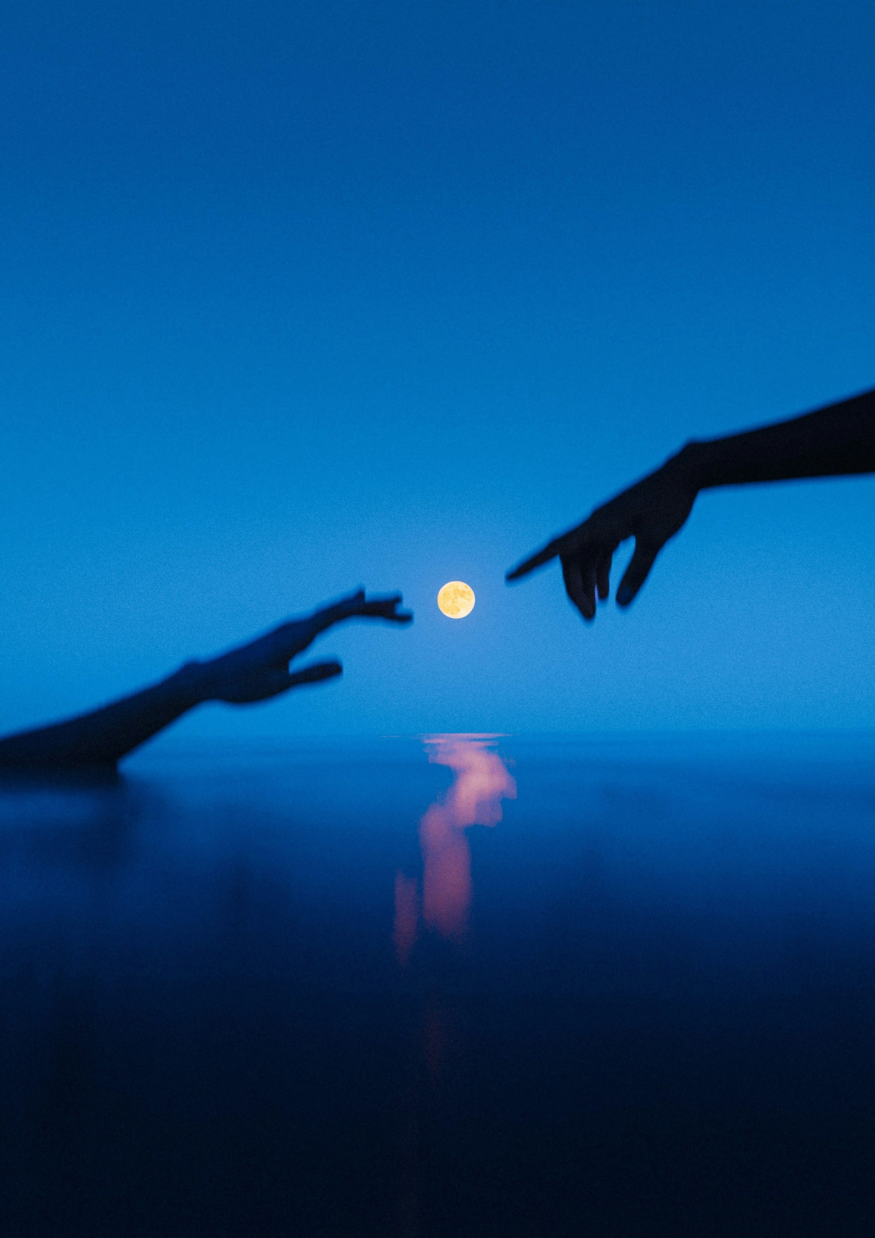 3000x4244 Two hands reaching out towards each other with a full moon in the background