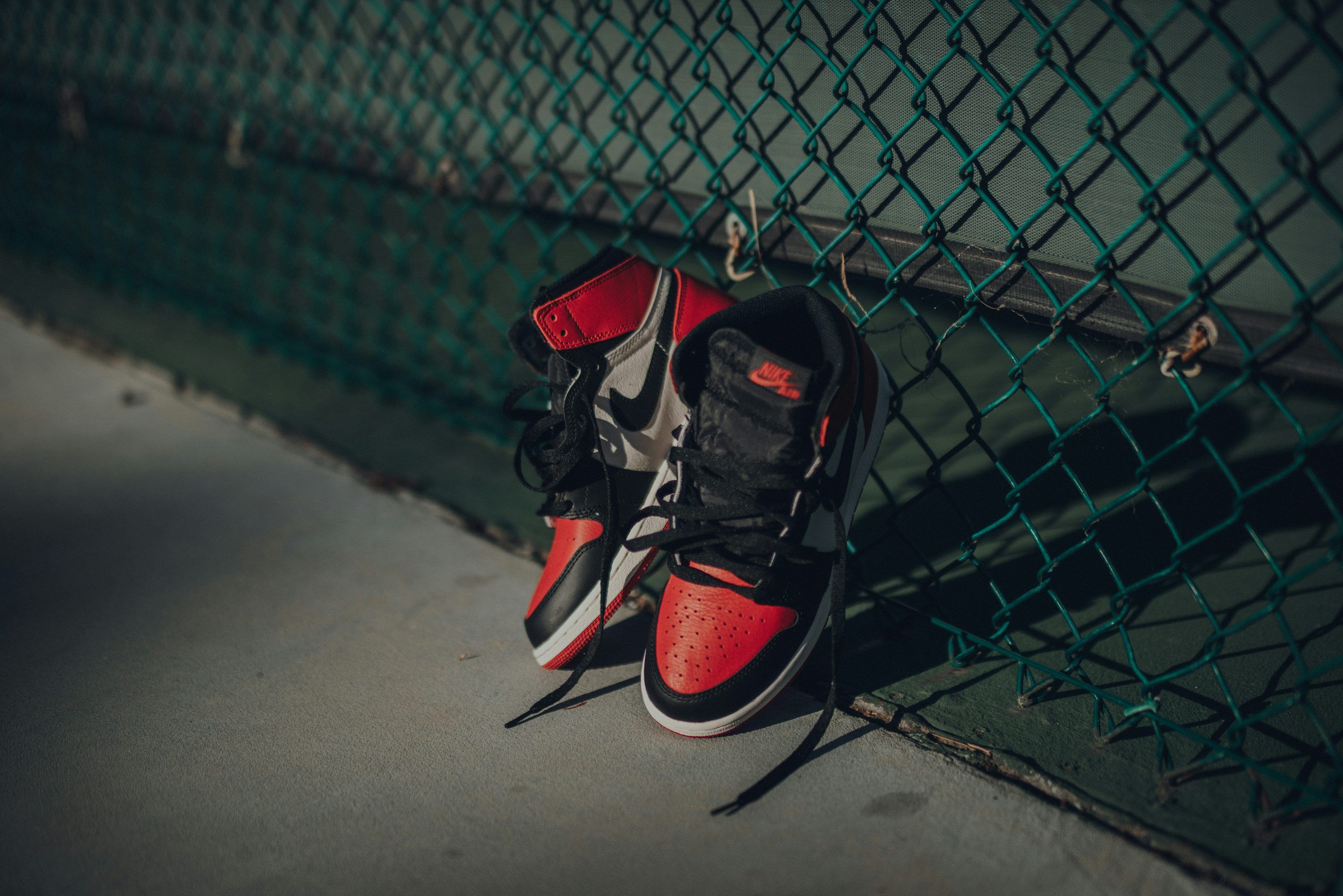 3000x2002 Nike Air Jordan 1 shoes near chain link fence
