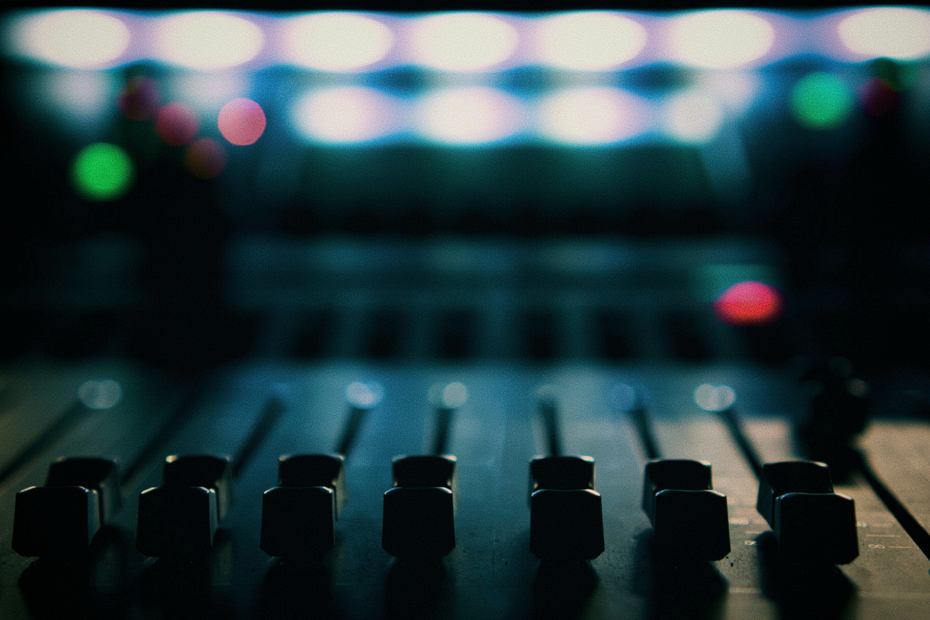 3000x2000 Sound mixer faders with colorful blurred lights in background