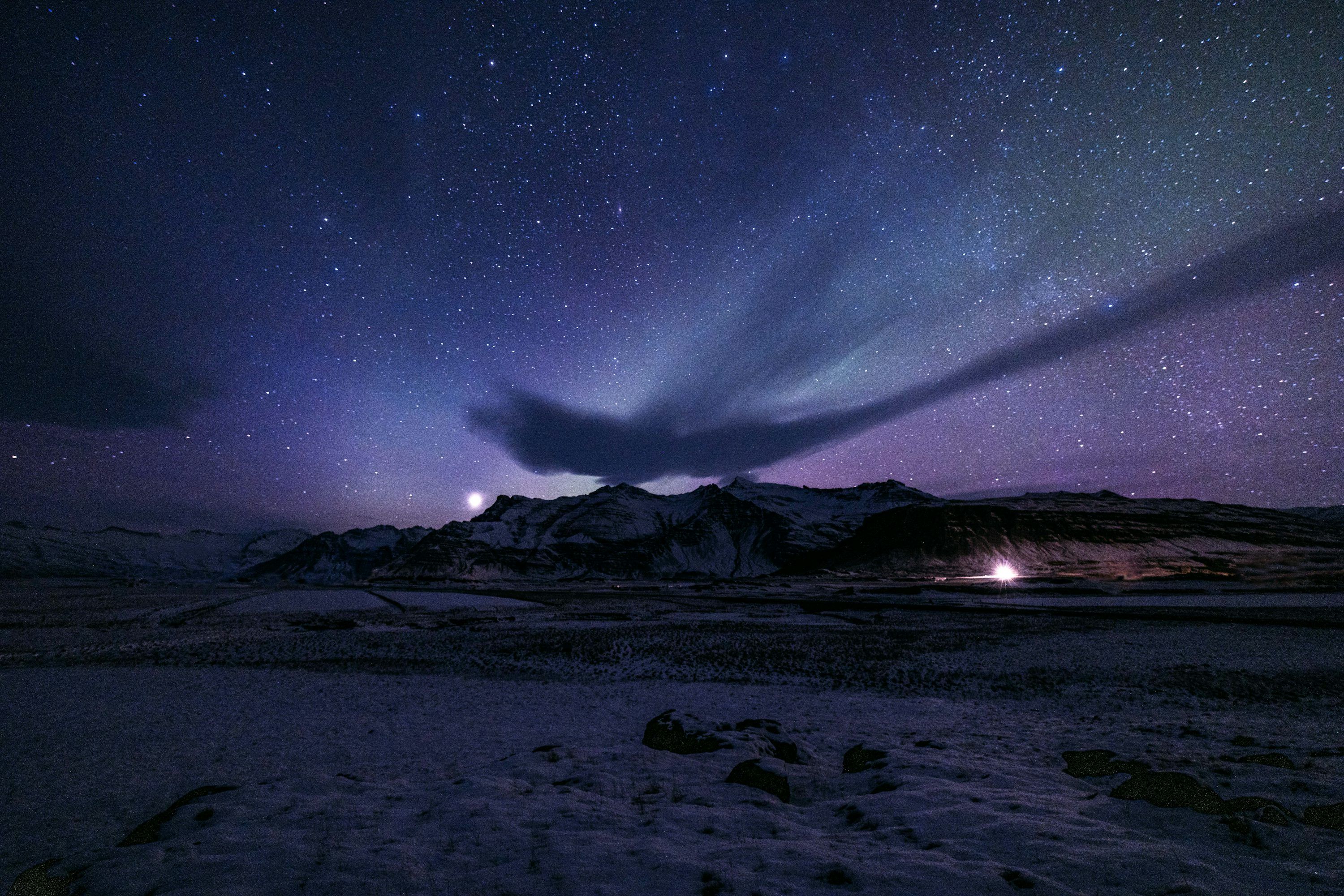 3000x2001 Northern lights illuminate a starry sky over snowy mountains