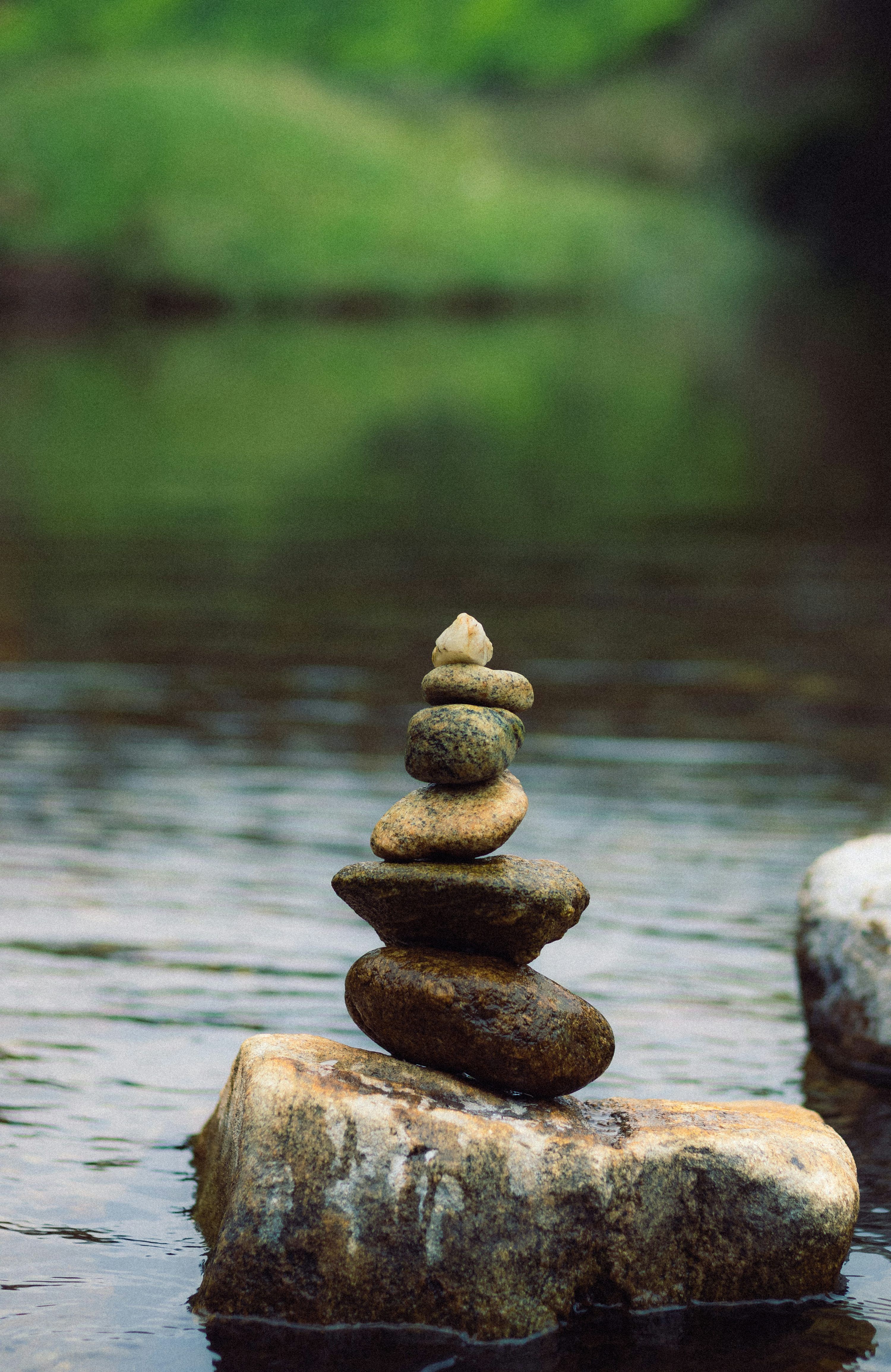 3000x4619 A stack of rocks sitting on top of a river