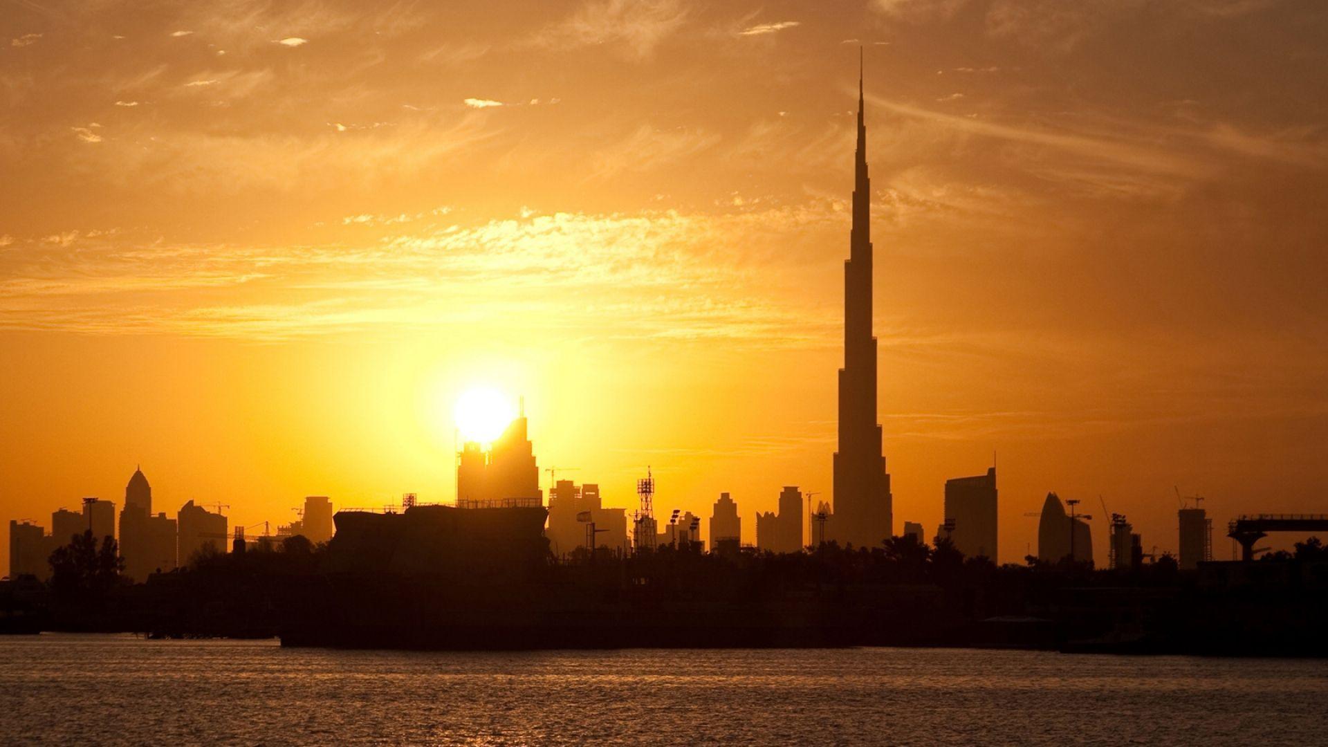 1920x1080 Download Wallpaper 1920x1080 dubai, buildings, houses, silhouette, sunset, distance, sky, clouds, tower, water, stroking Full HD 1080p HD Background