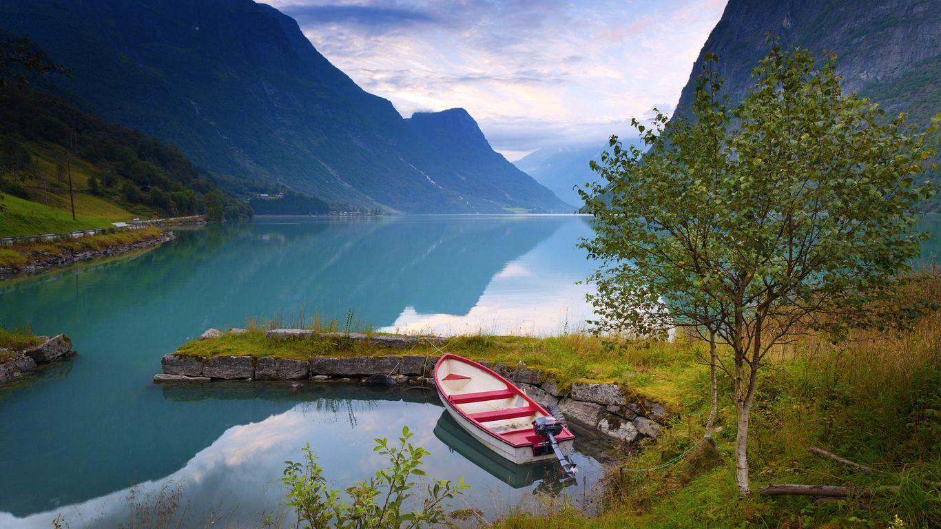 1366x768 Download wallpaper 1366x768 norway, boat, mountains, blue water, lake, coast, stones, grass tablet, laptop HD background
