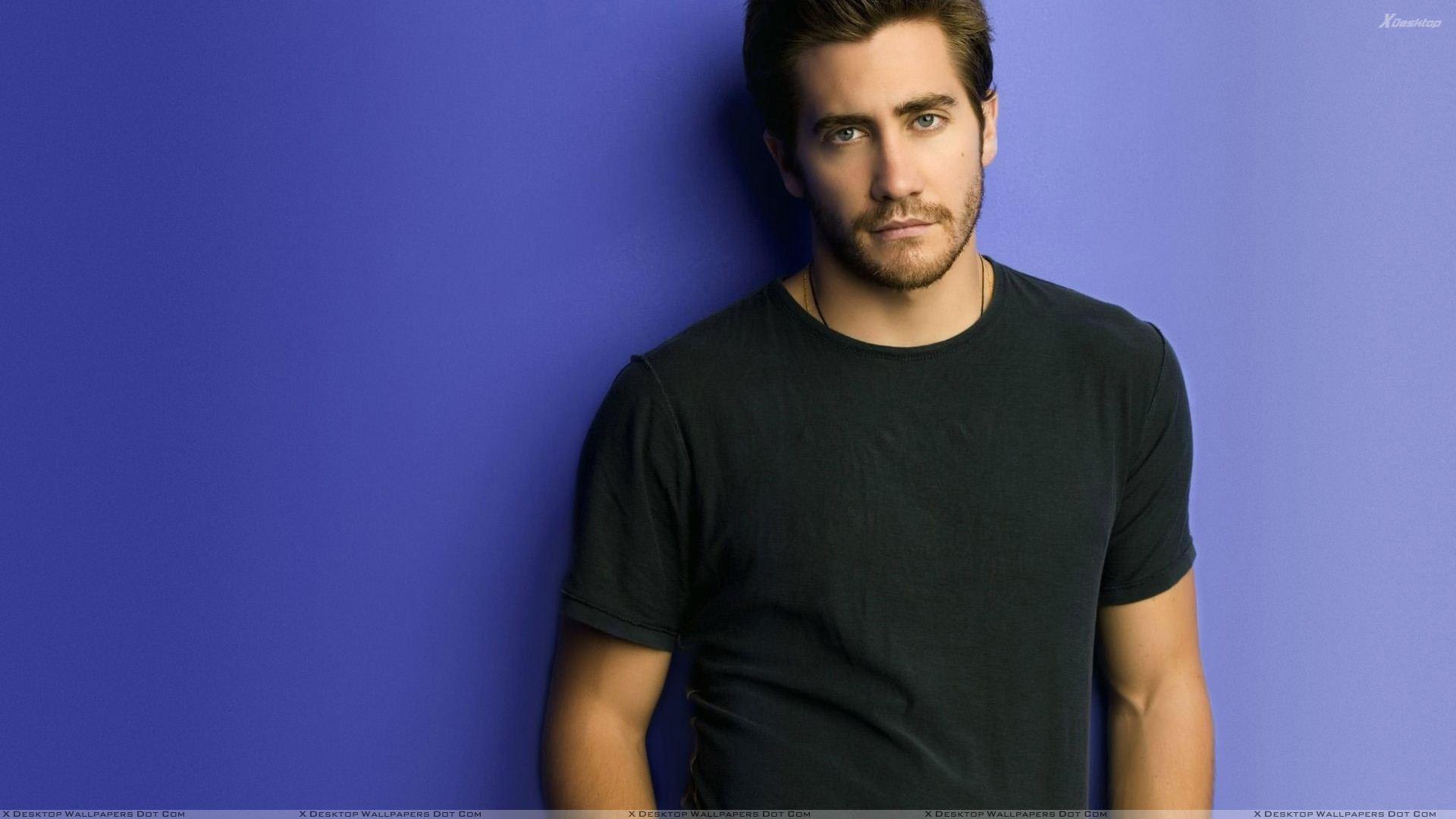 1920x1080 Jake Gyllenhaal Looking Smart In Black T Shirt N Blue Background Wallpaper
