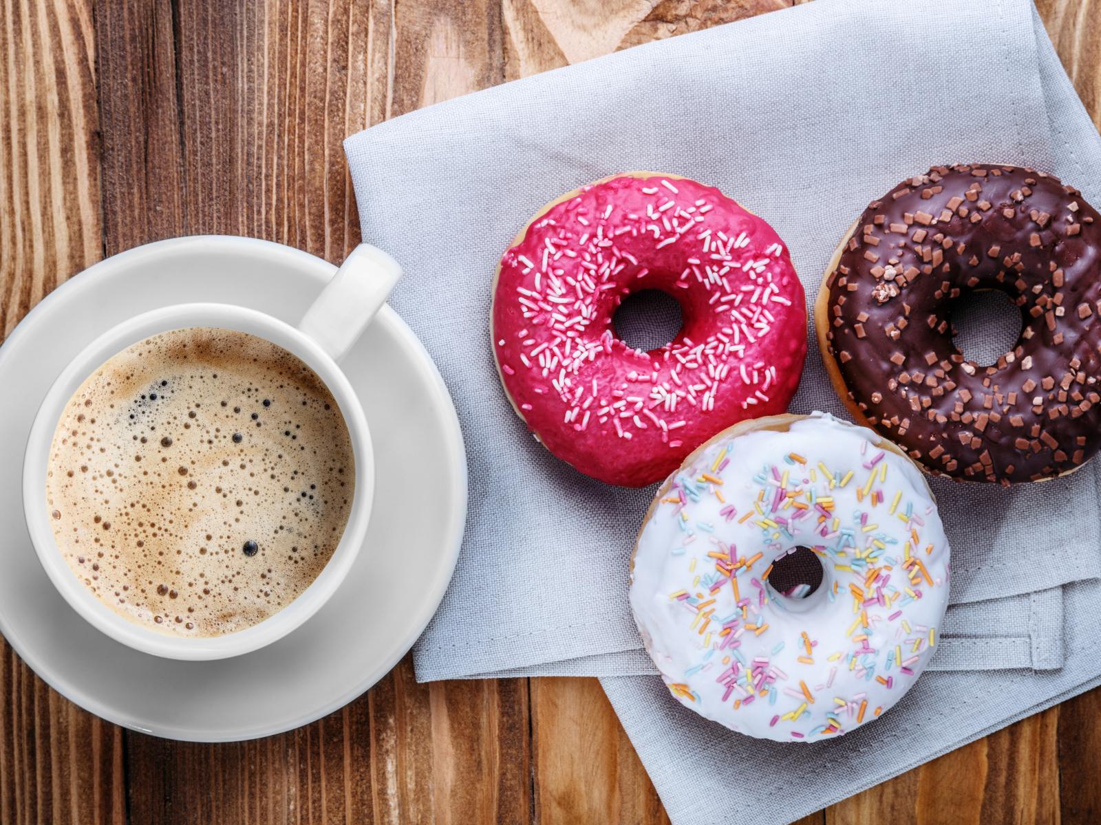 1600x1200 A cup of coffee with three appetizing donuts on a table Desktop wallpaper 1600x1200