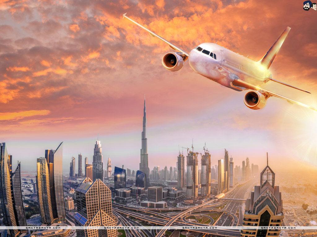 1024x768 An airplane flying over Dubai against colorful sunset in United Arab Emirates