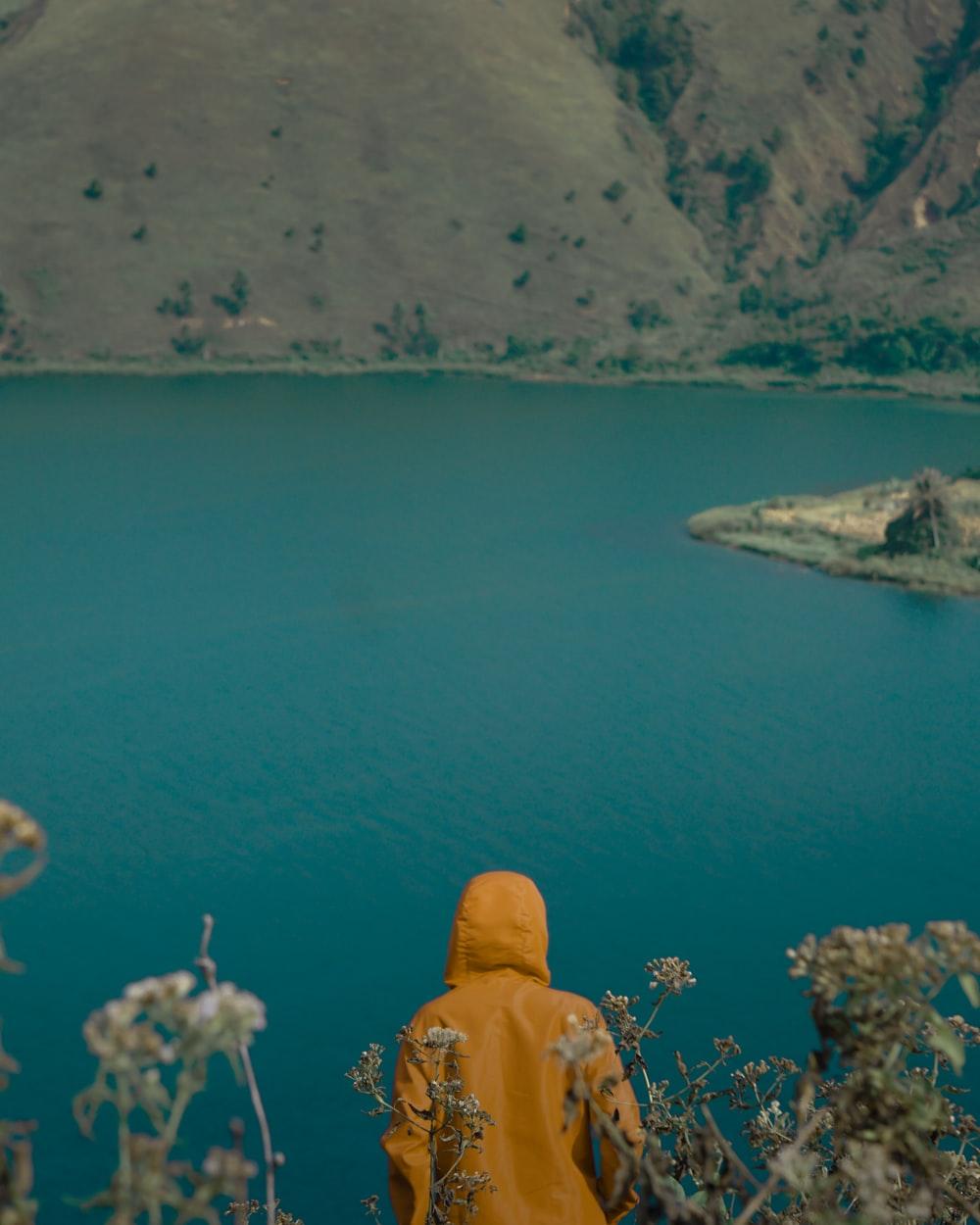 1000x1250 person standing on high grounds looking at calm waters photo