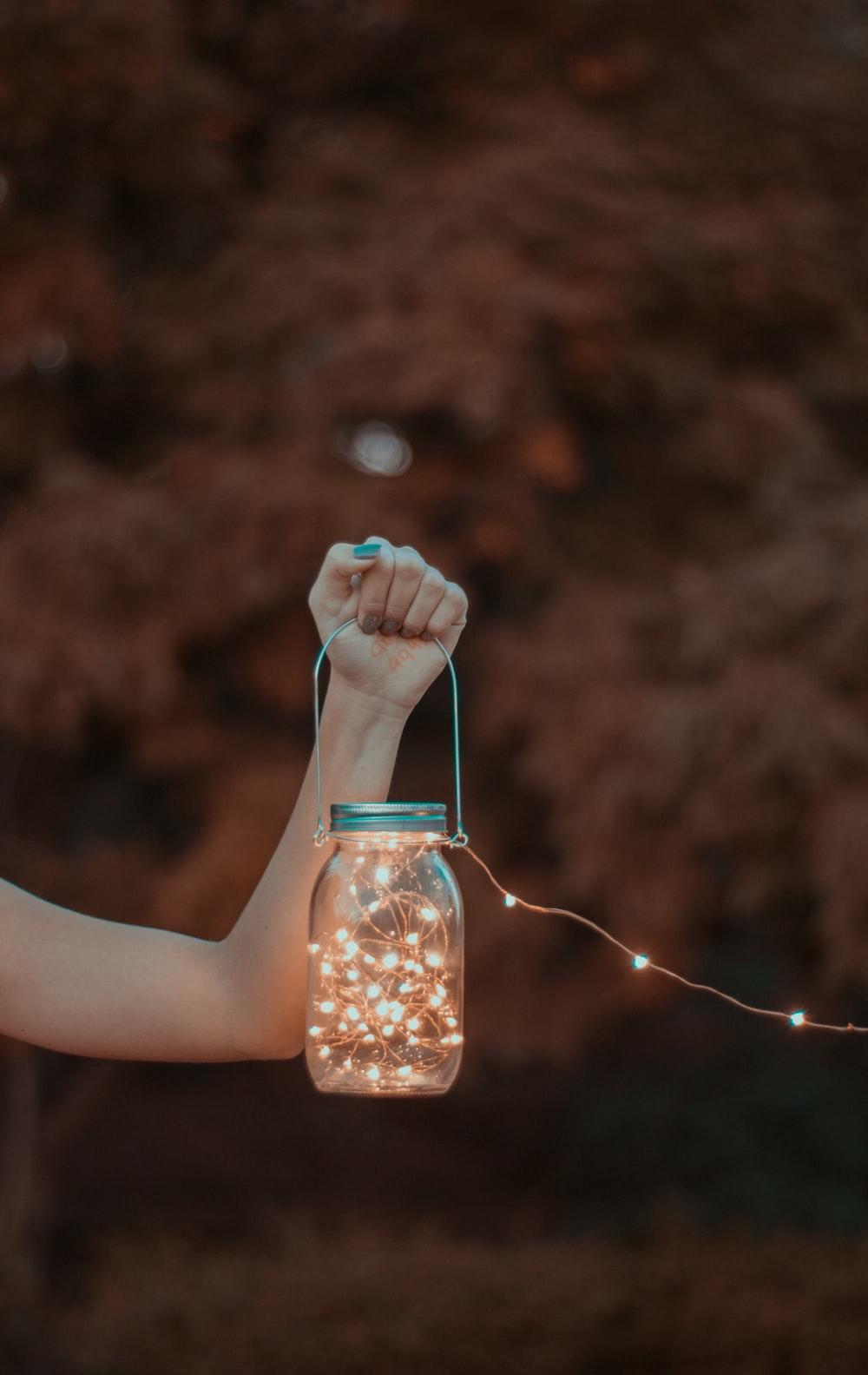 1000x1583 person holding mason jar with string lights photo