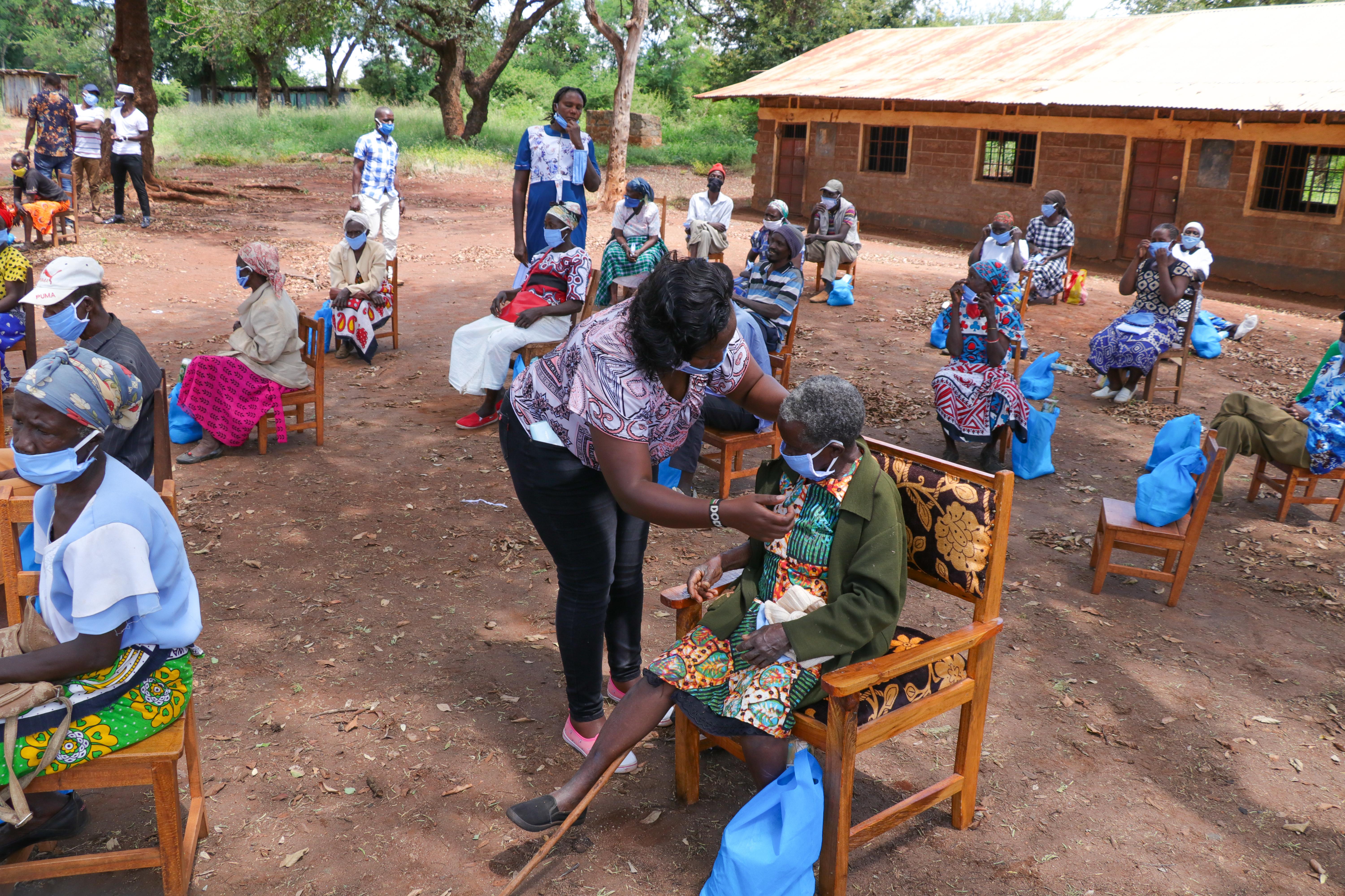 6000x4000 Black elderly people sitting on chairs in yard of hospital in poor African village · Free
