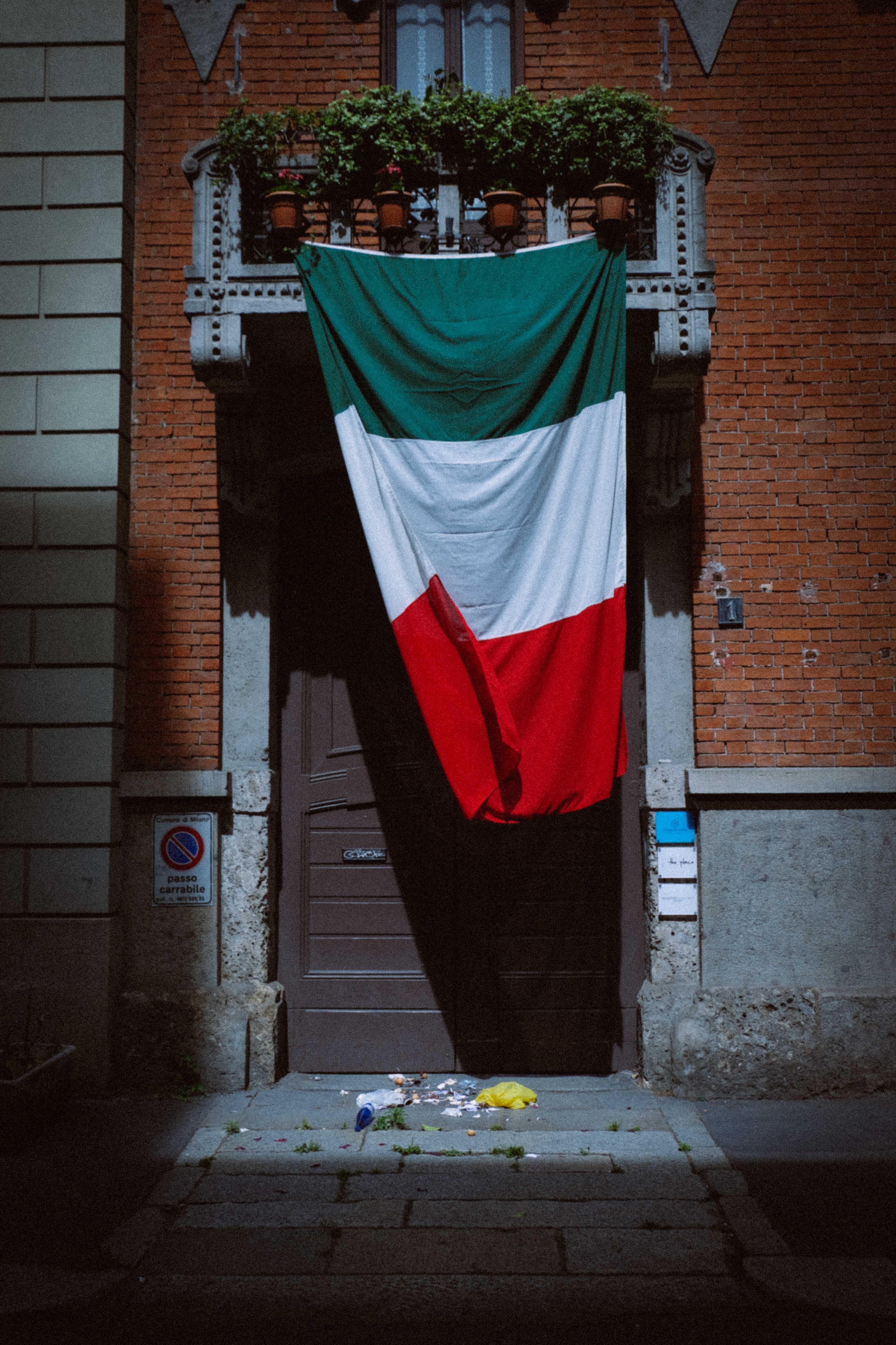 3967x5950 Italian flag hanging on entrance of brick house · Free