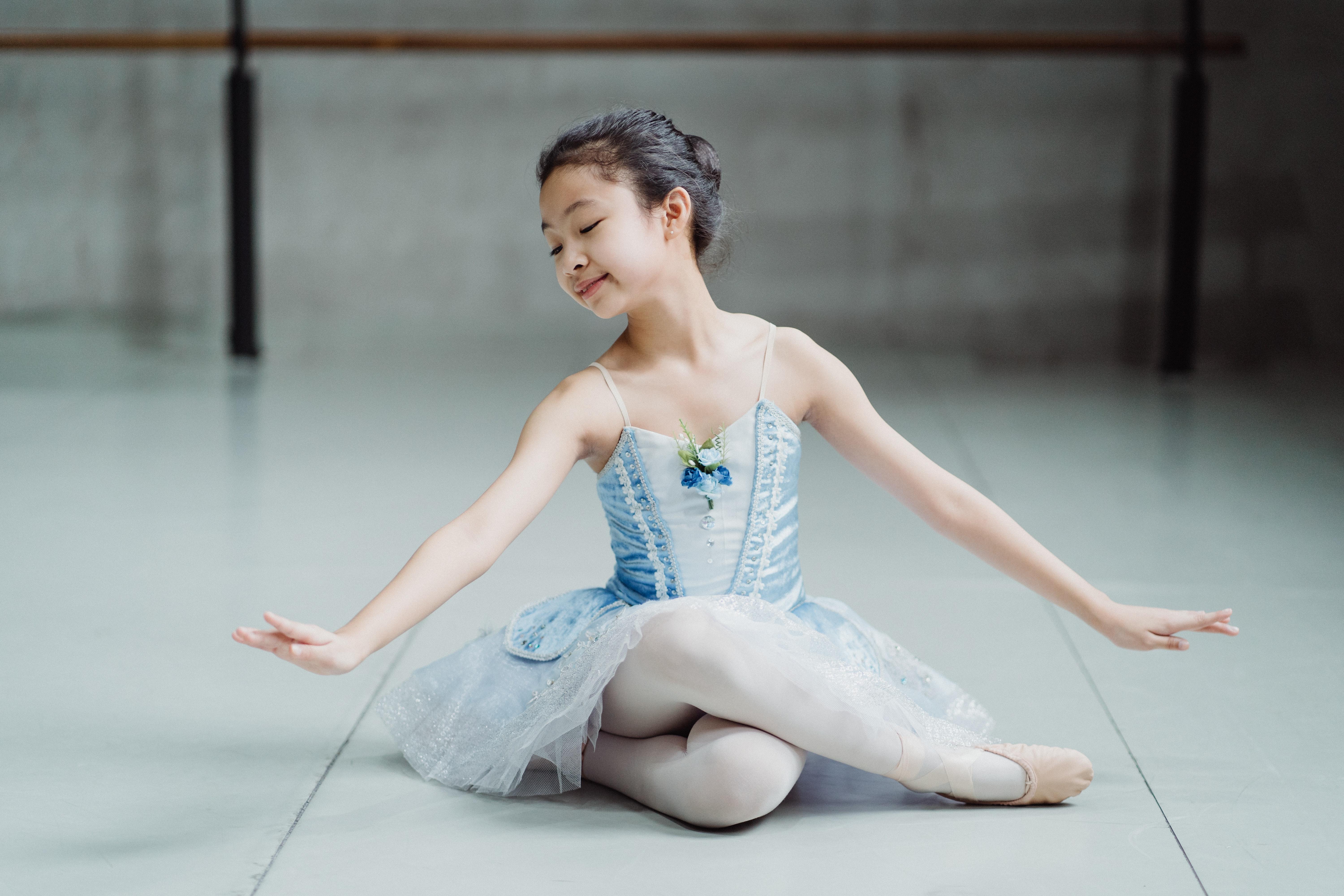 6000x4000 Little ethnic charming ballerina sitting on floor in ballet studio · Free