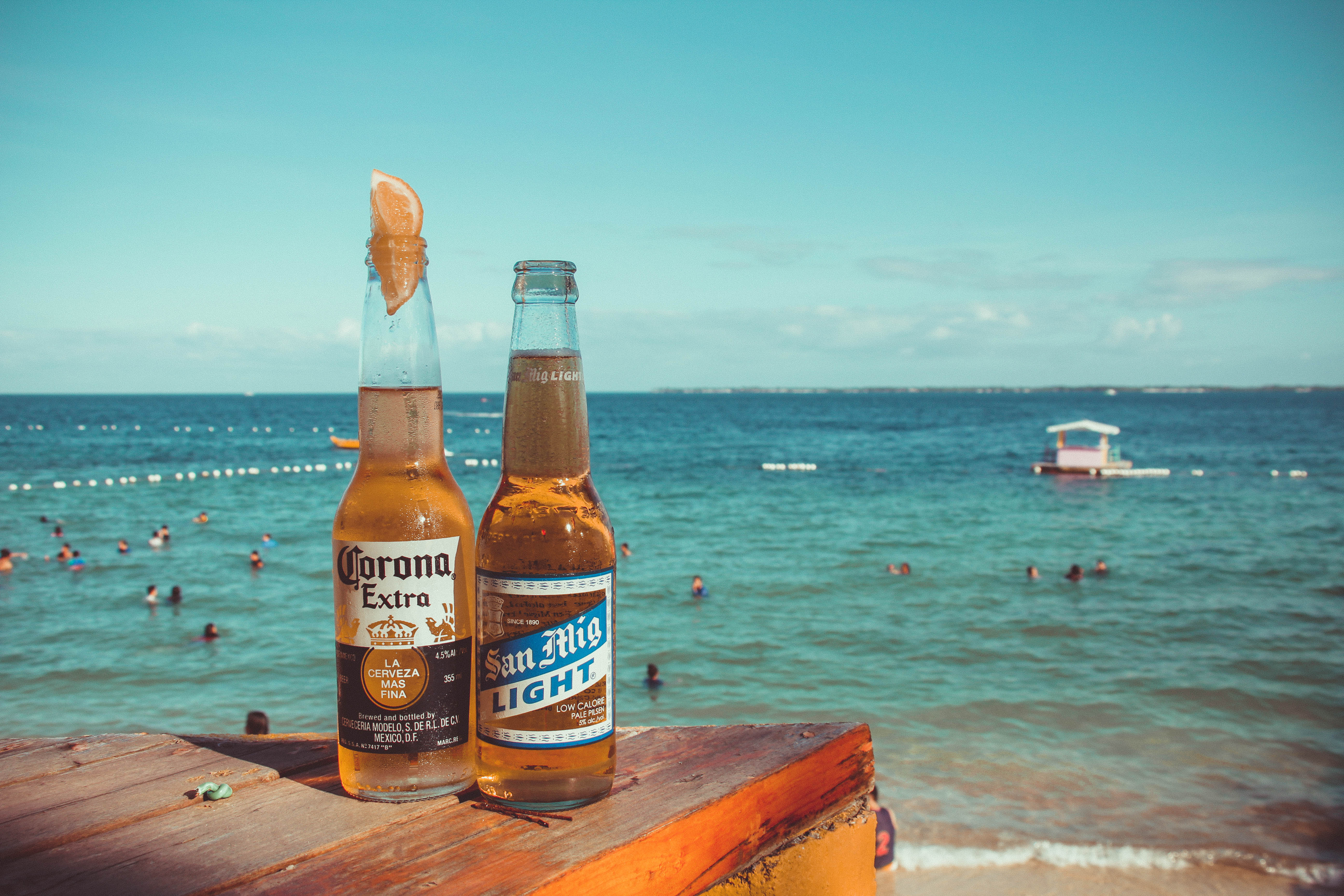 5184x3456 Two Corona Extra and San Mig Light Beers on Top of Brown Wooden Plank Near Beach · Free