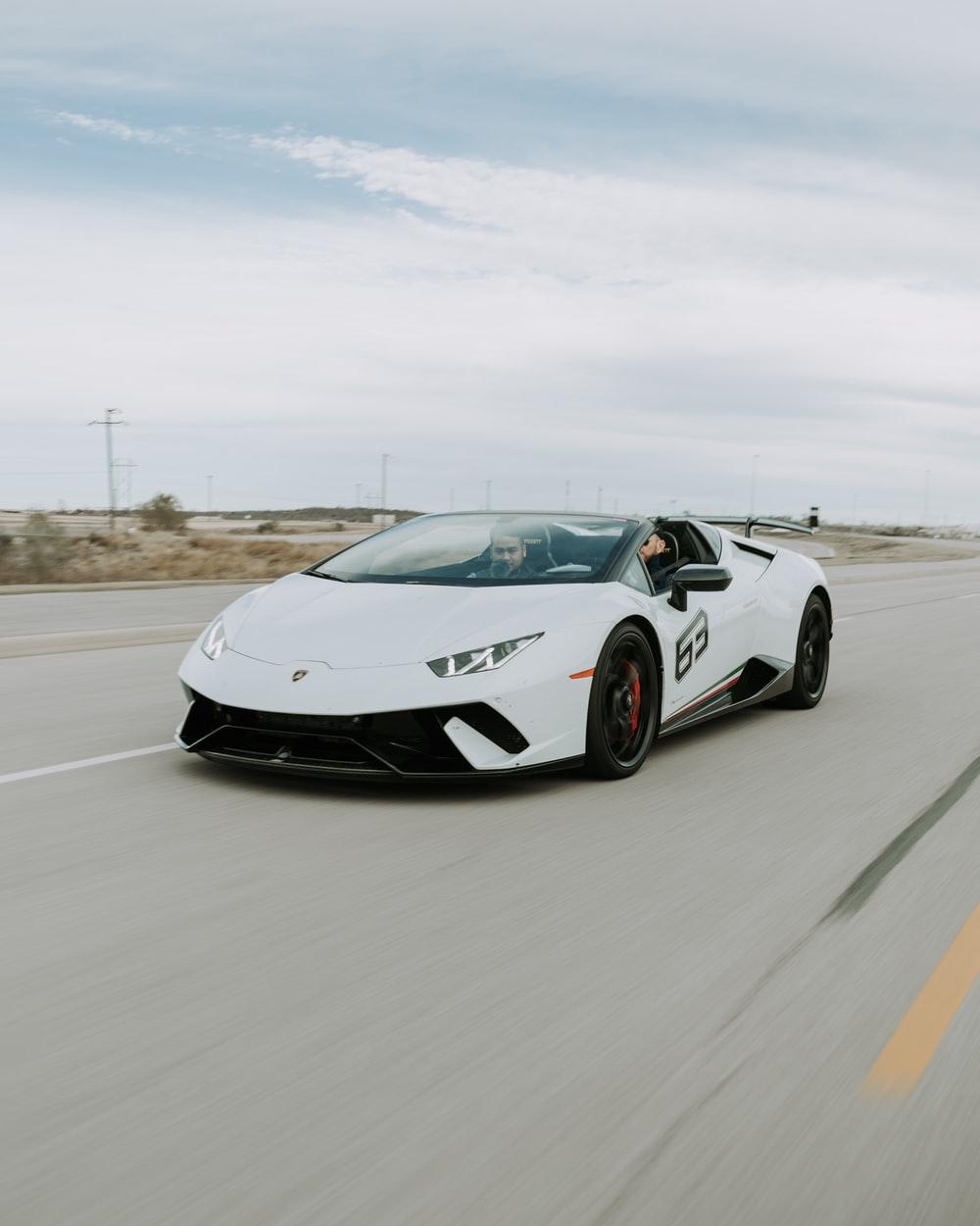 1000x1250 two men driving white Lamborghini Huracan Spyder during daytime photo