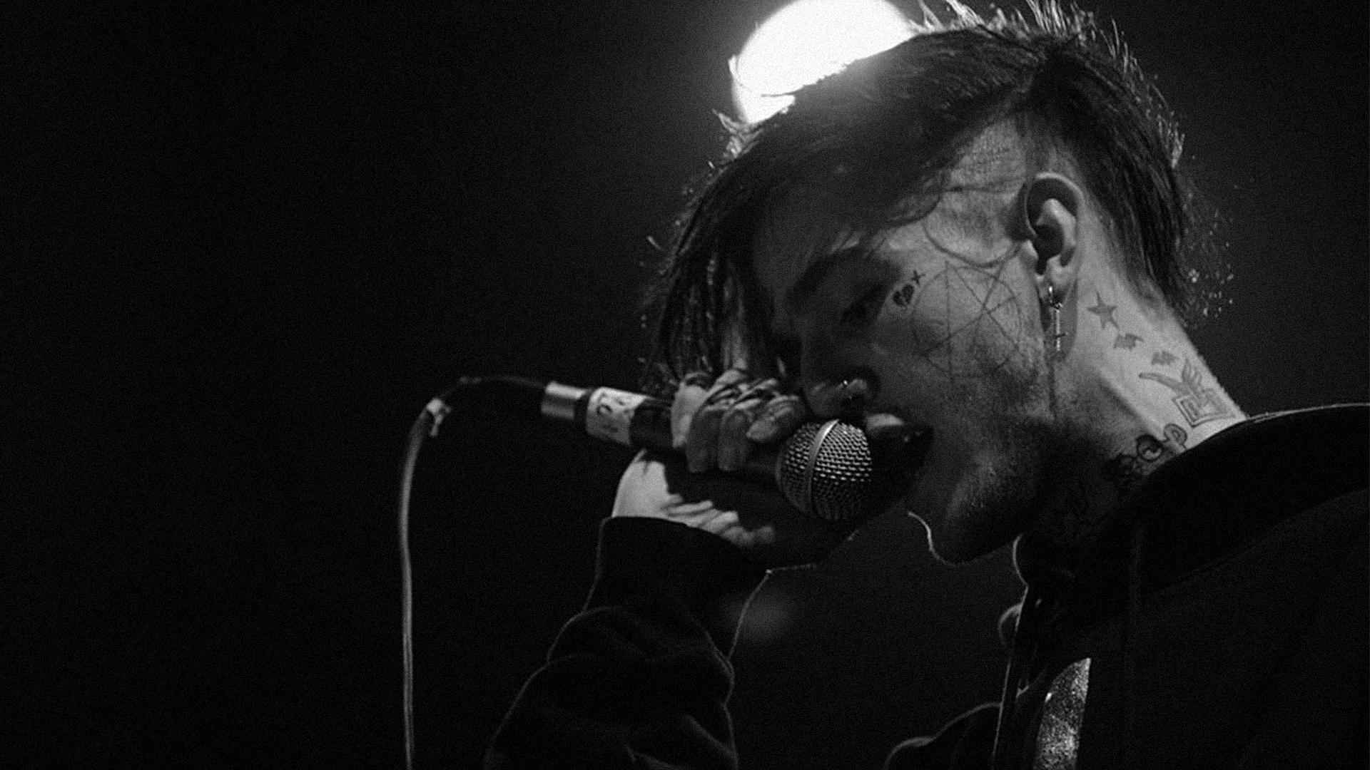 1920x1080 lil peep is singing with mike wearing black coat in black background with light on top HD music Wallpaper
