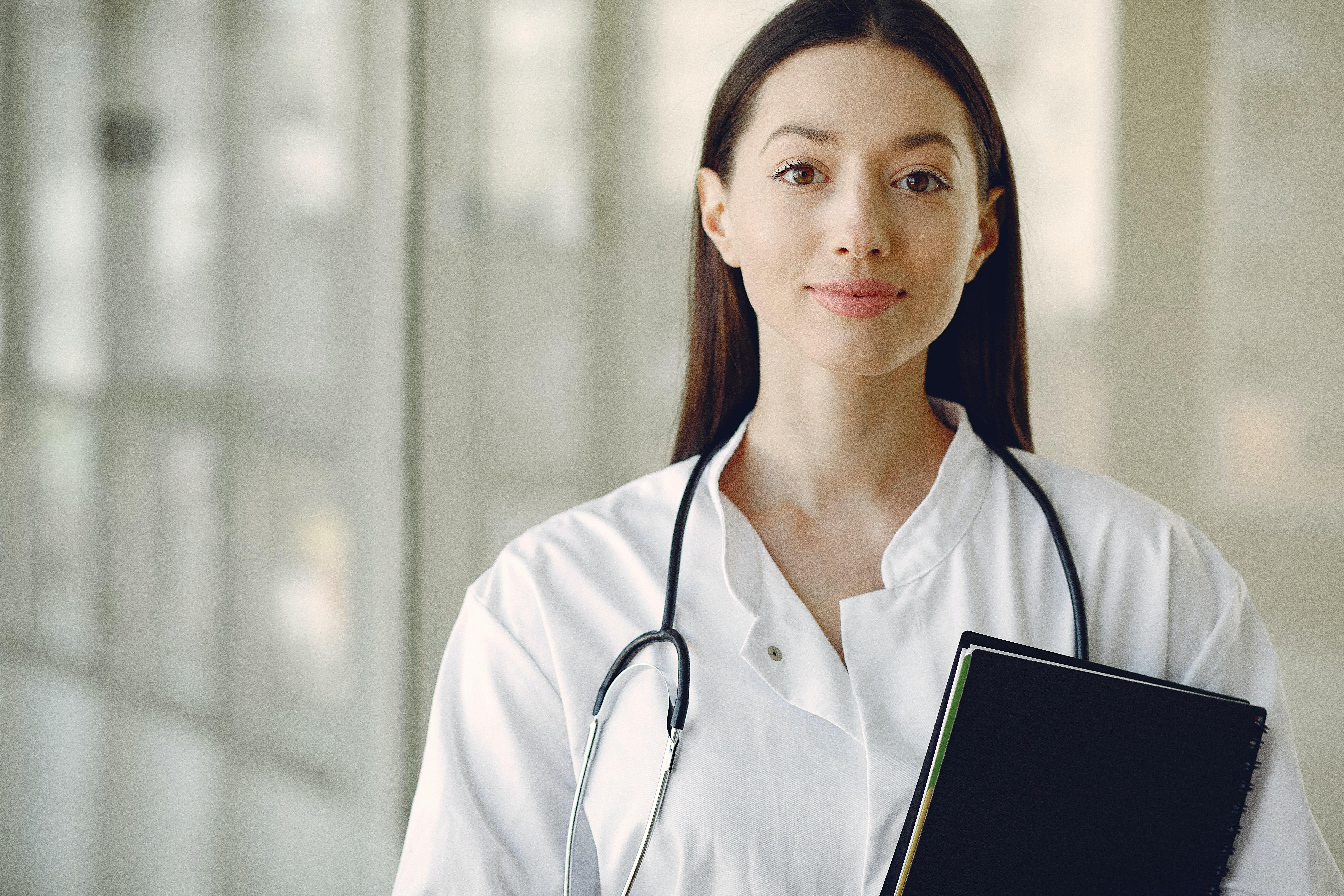 6720x4480 Young doctor in uniform with stethoscope and notebook in medical room · Free