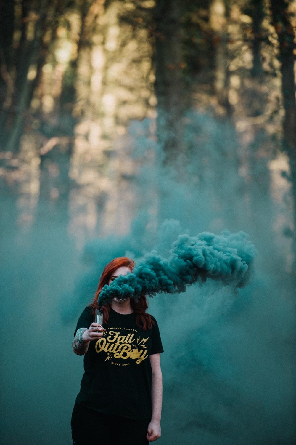 1000x1502 woman holding vaporizer releasing blue smoke near forest photo