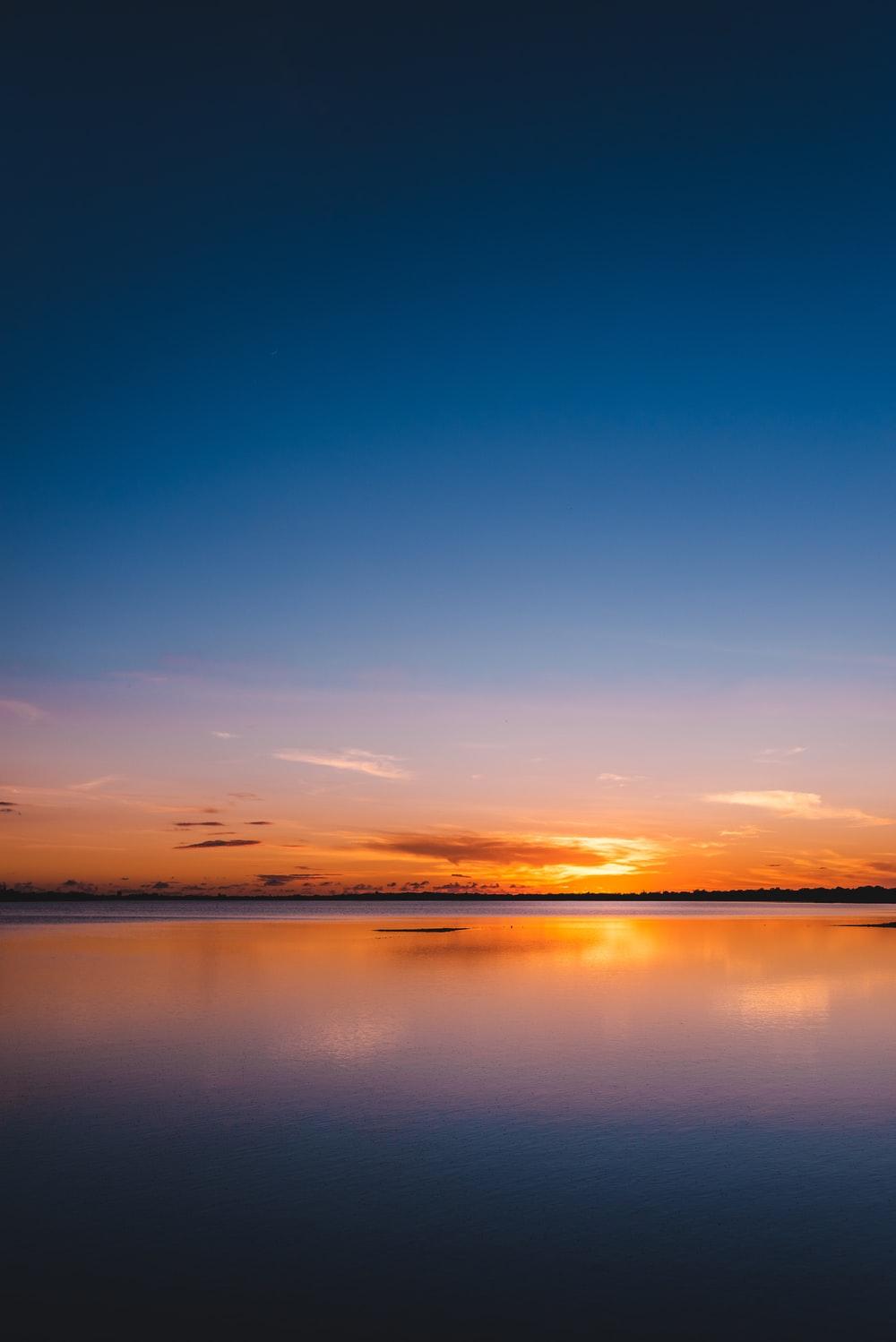 1000x1498 orange and blue sky with calm body of water photo