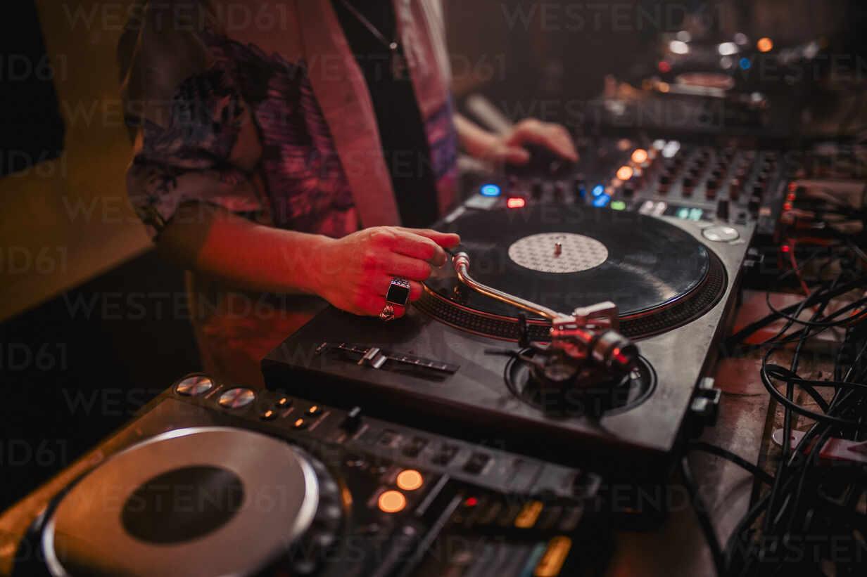 1232x821 Side view of crop male DJ mixing music on controller during concert in dark nightclub stock