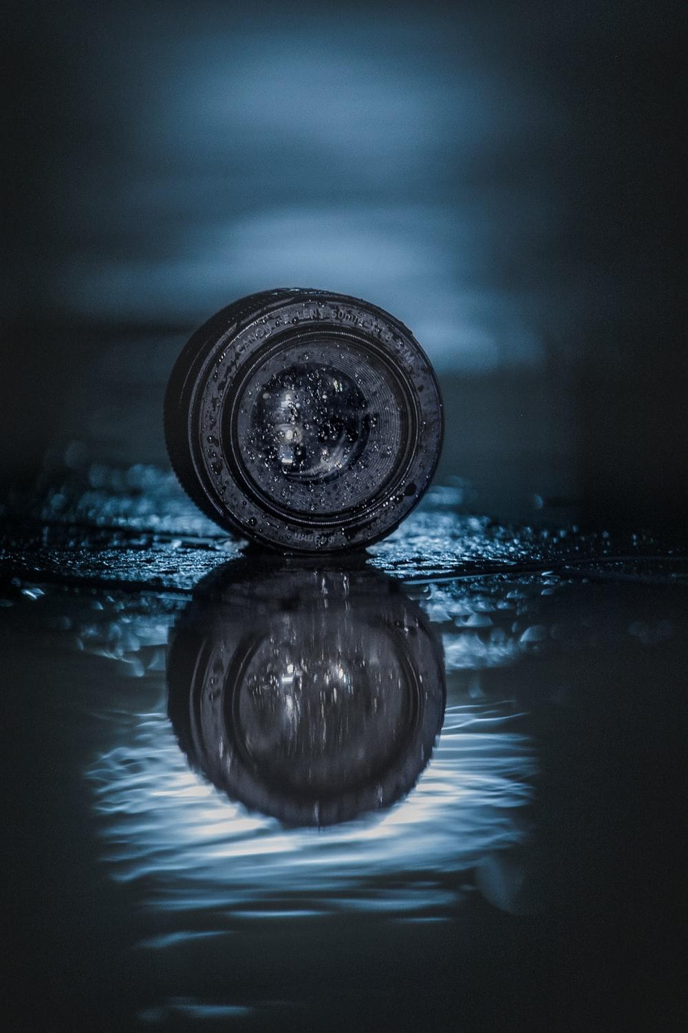 1000x1500 round black smartphone lens with reflection on water digital wallpaper photo