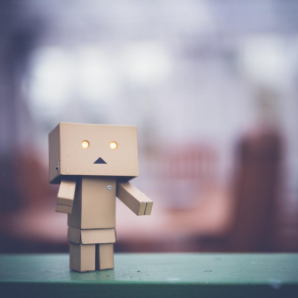 1000x1000 brown cardboard robot on green table photo