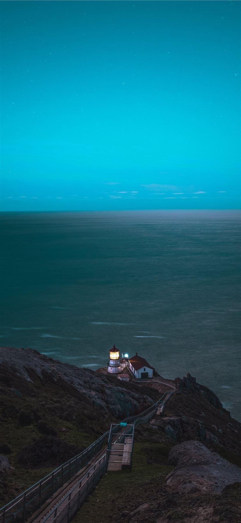 828x1792 brown and white house on cliff in front of sea iPhone 11 Wallpaper Free Download