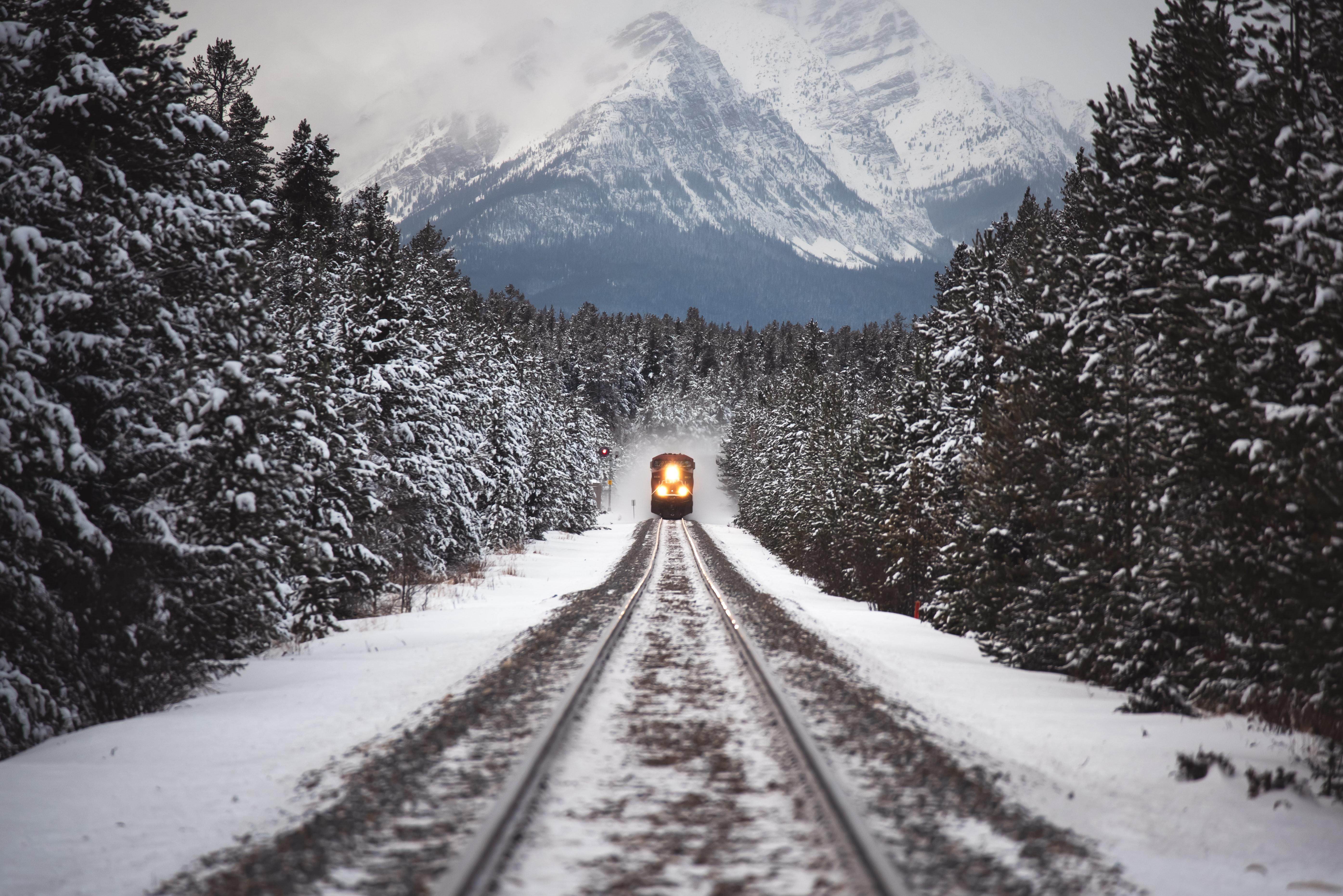 5579x3724 Train Moving Through A Snow Covered Mountain Forest